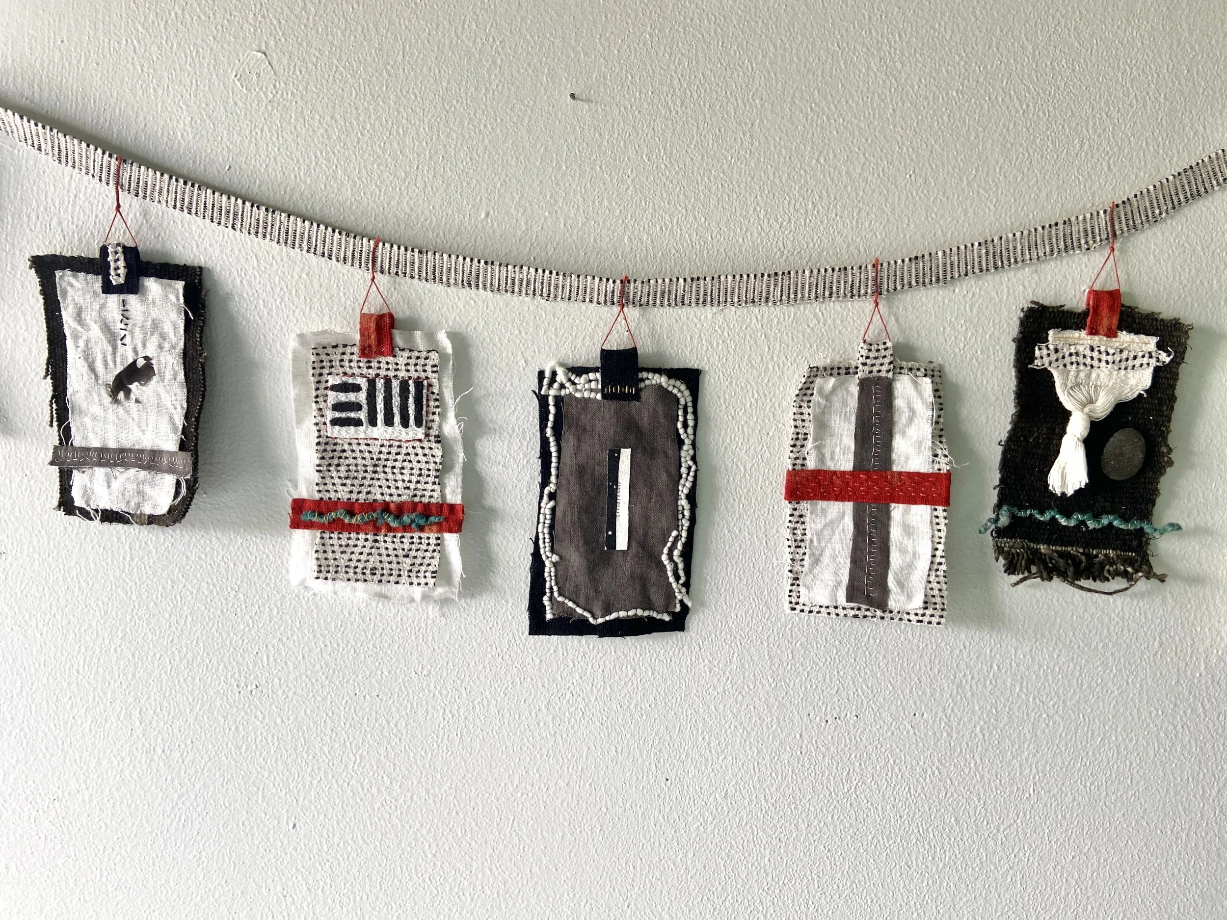 Mixed media wabi sabi prayer flags created by Emma Freeman in Wisconsin using repurposed fabric, textiles, found nature, slow stitching, and hand embroidery, mark making, abstract art compositions and expressions, black, white, red and grey prayer fl