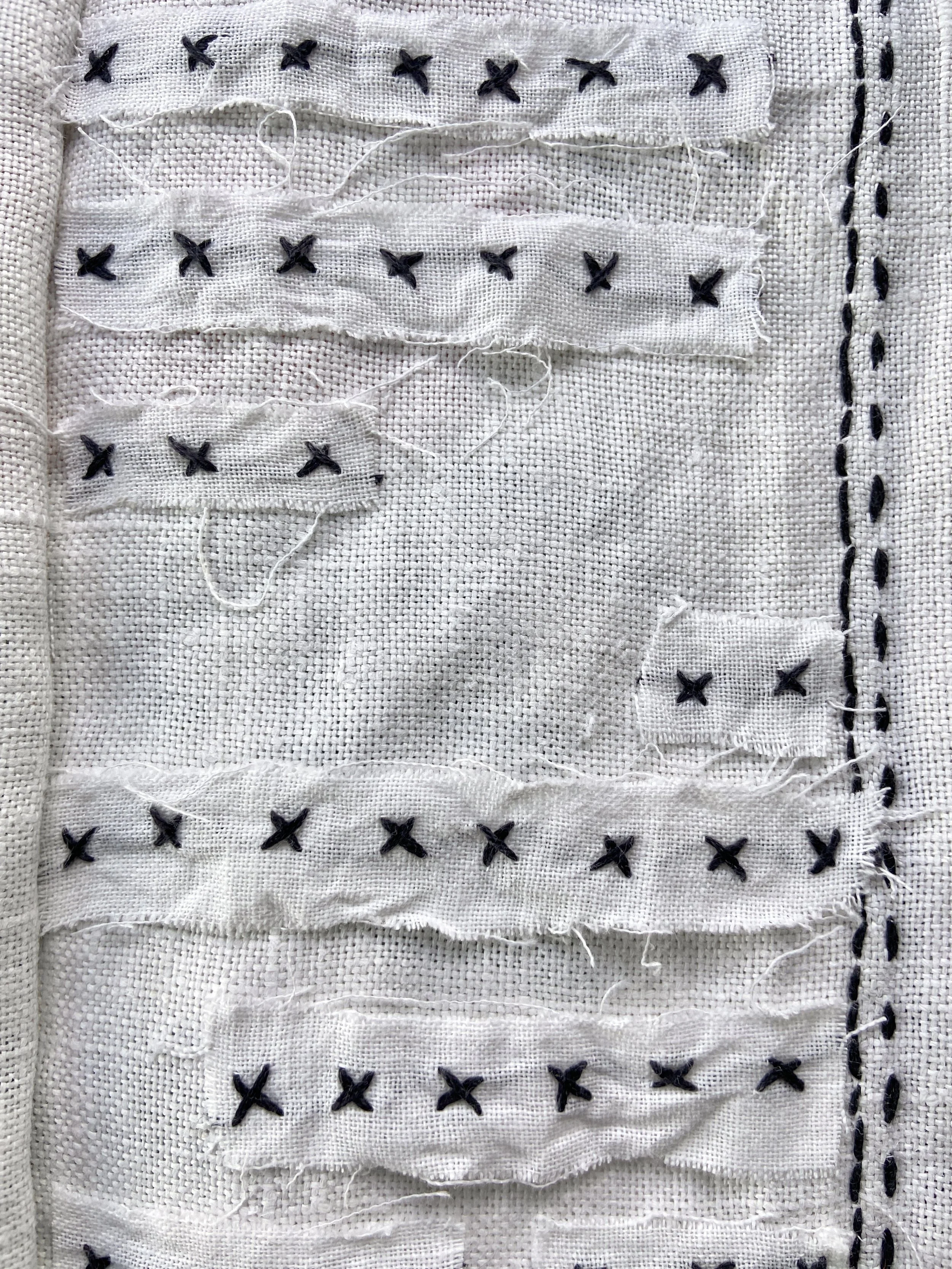 Vintage cross stitched embroidery linen tablecloth transformed into a slow stitched fabric meditation book by Emma Freeman, contemplative textile artist and mixed media artist in Wisconsin. She uses appliqué techniques and other intuitive hand embroi