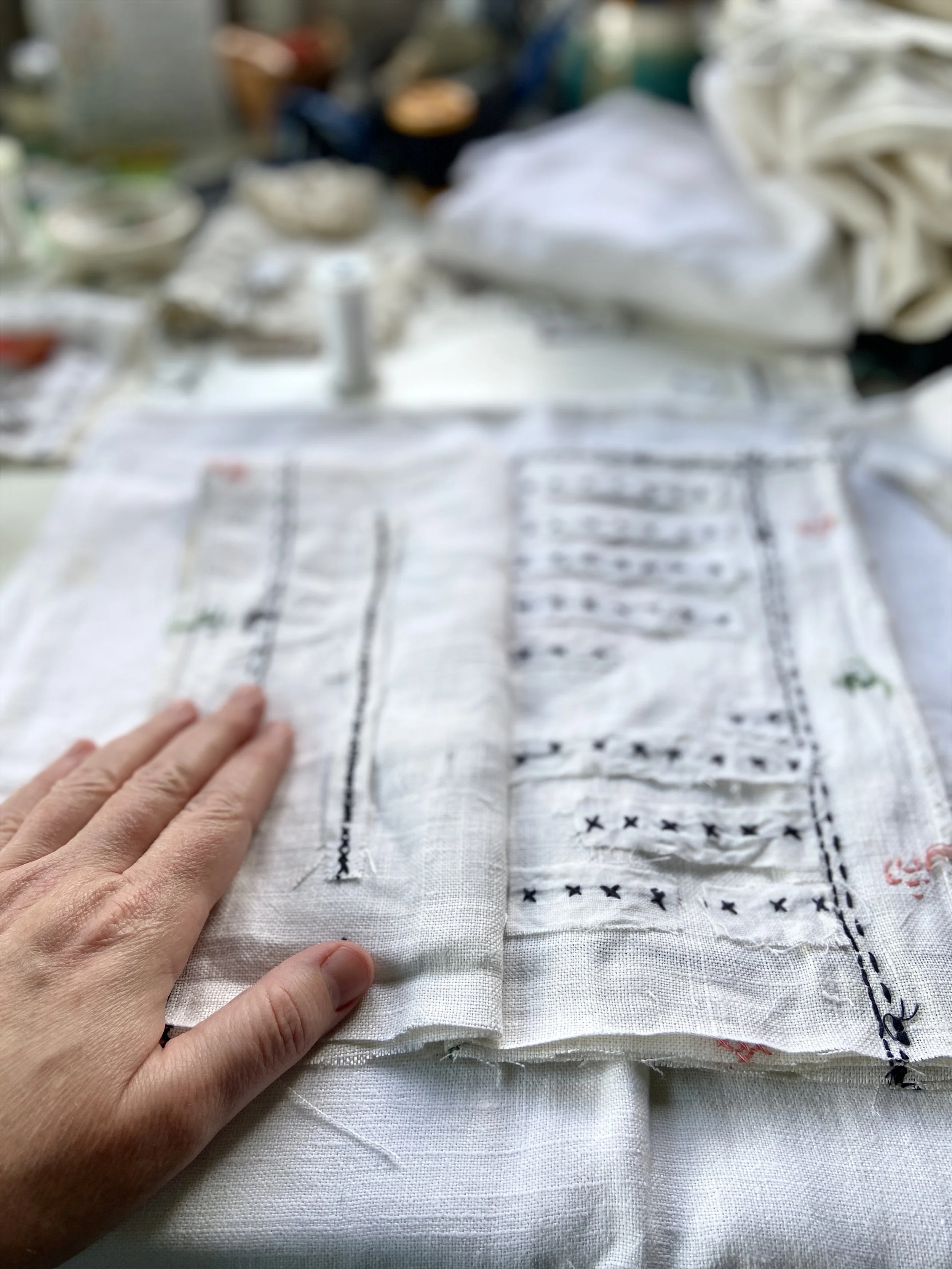 Vintage cross stitched embroidery linen tablecloth transformed into a slow stitched fabric meditation book by Emma Freeman, contemplative textile artist and mixed media artist in Wisconsin. She uses appliqué techniques and other intuitive hand embroi