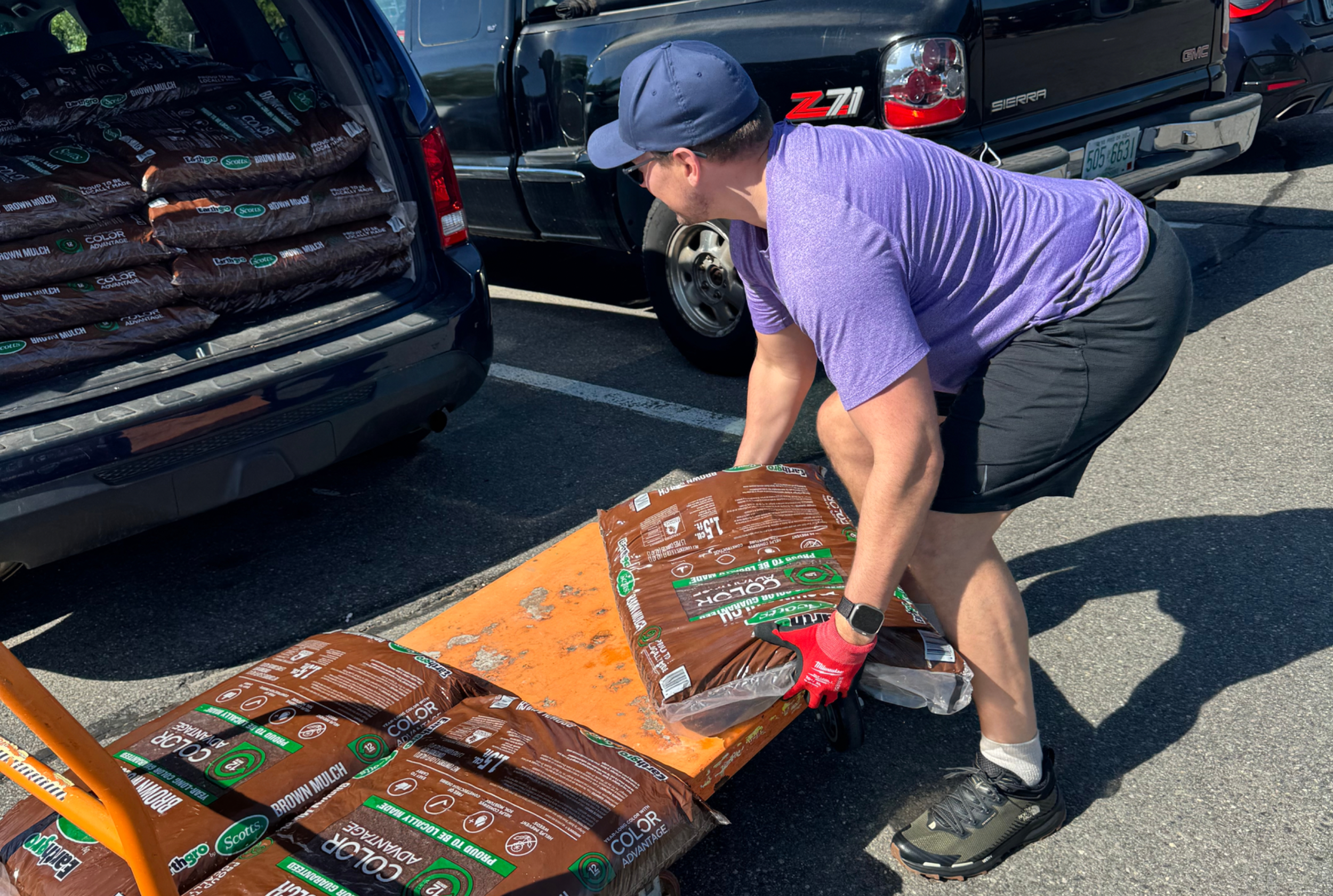 Dr. Jeff Newman demonstrating proper lifting technique while lifting a bag of mulch, ensuring back safety and promoting good form