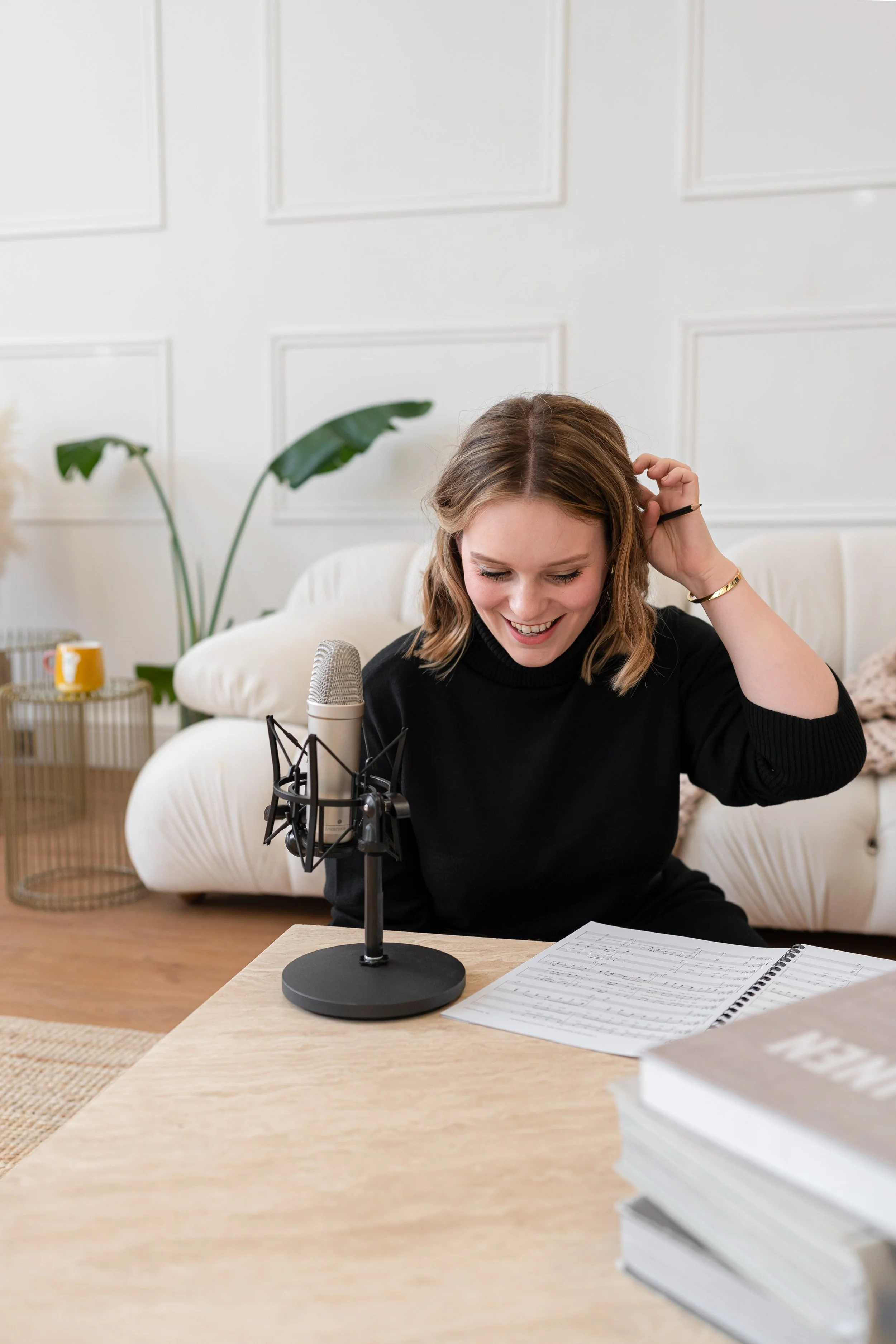 Singer brand photography by Photography by Trish - woman smiling at a microphone in a light and airy home studio, Cambridge brand photographer, UK