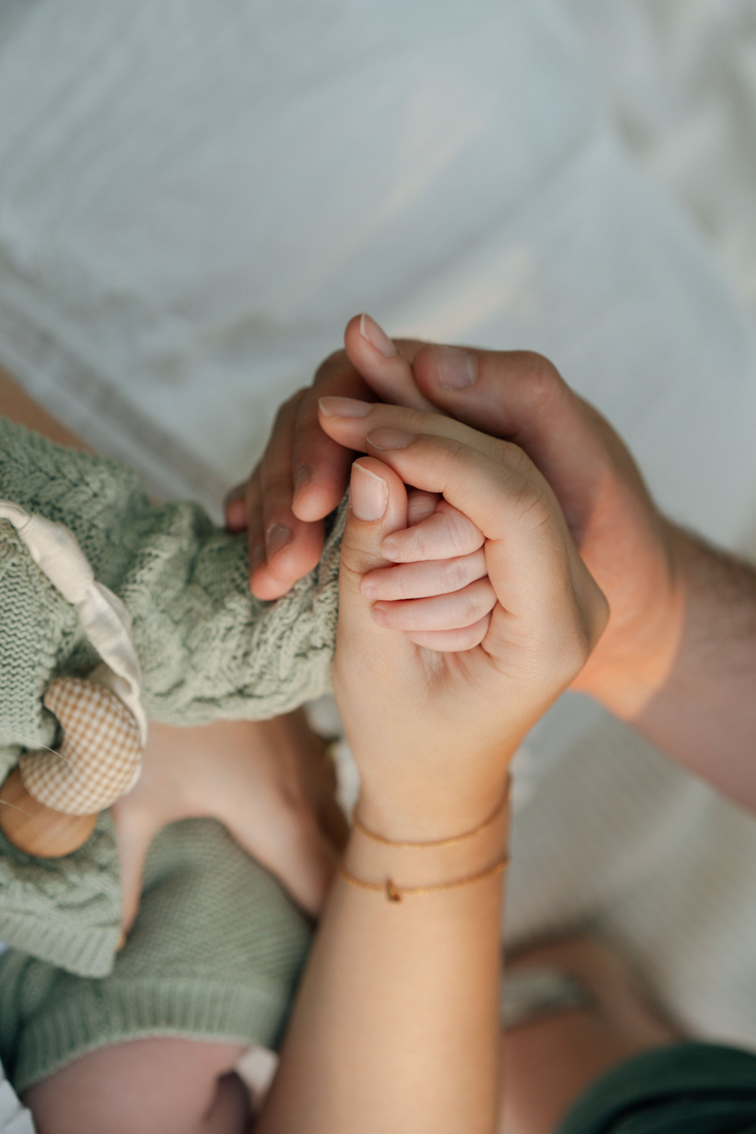 An adult and a child holding hands, with the child's hand resting on the adult's palm.