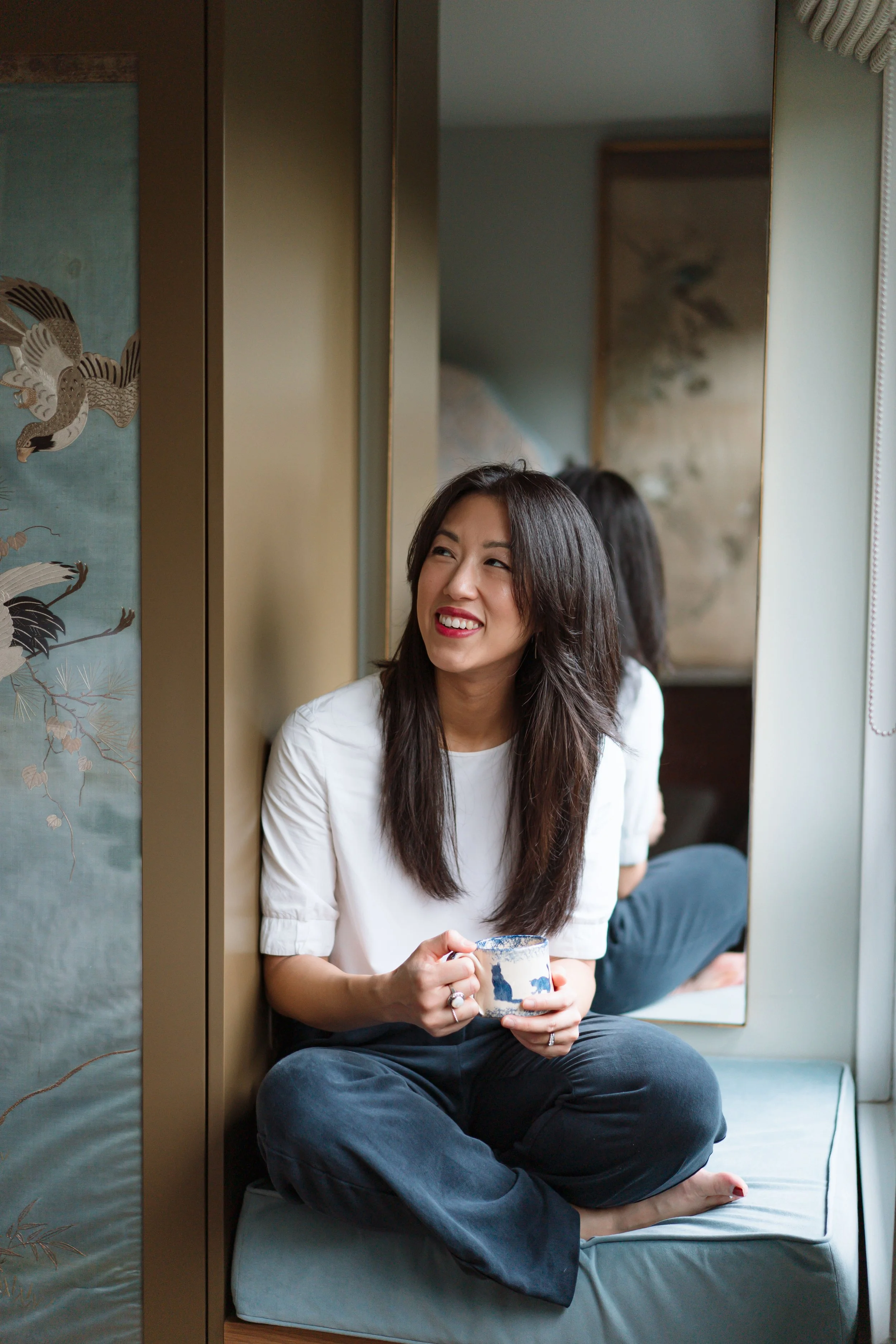 Personal brand photography by Photography by Trish - woman sitting cross-legged with a drink, reflected in a mirror, relaxed natural brand session, Cambridge, UK