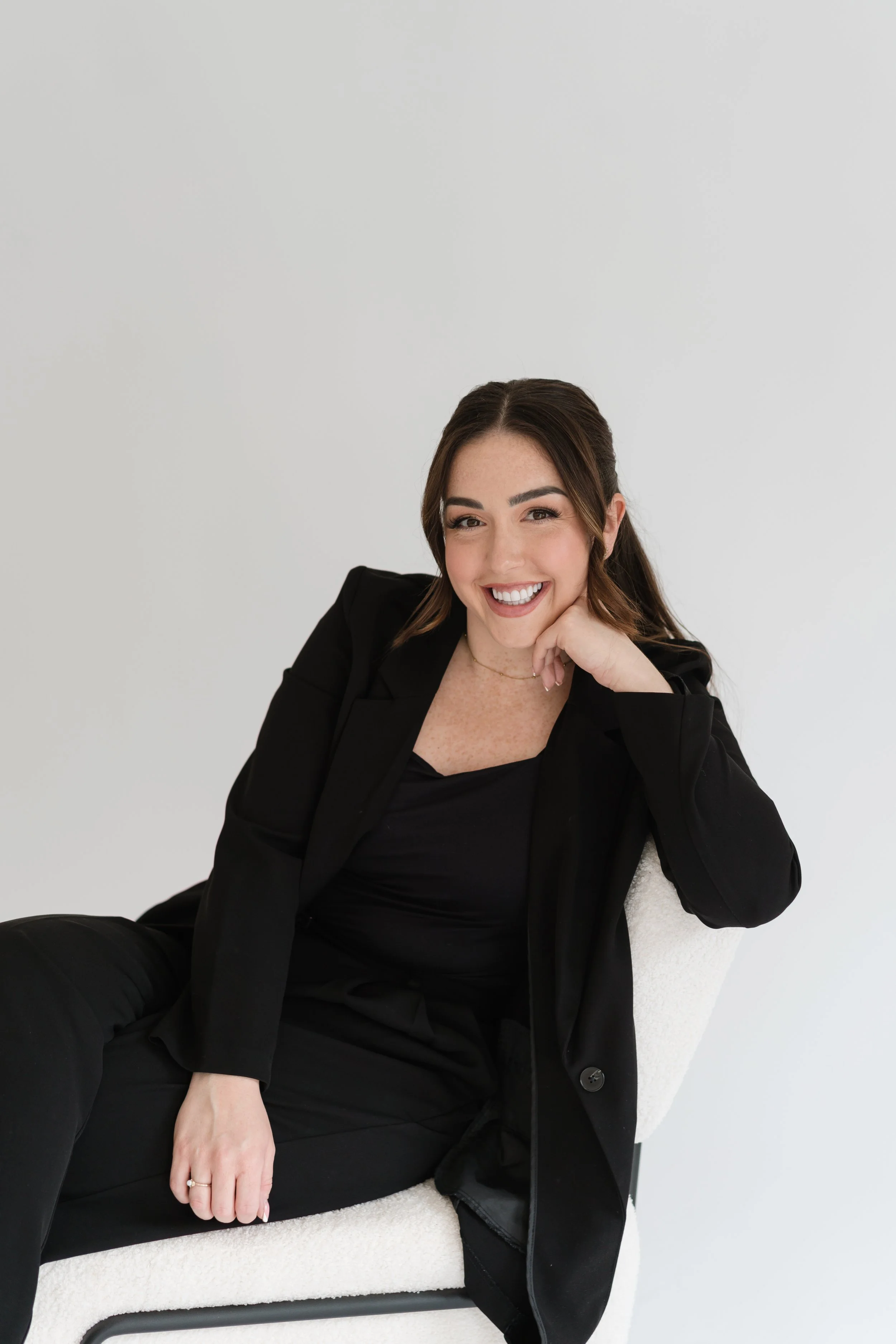 Personal brand photography by Photography by Trish — confident woman in black outfit smiling in a clean studio setting, Cambridge brand photographer, UK