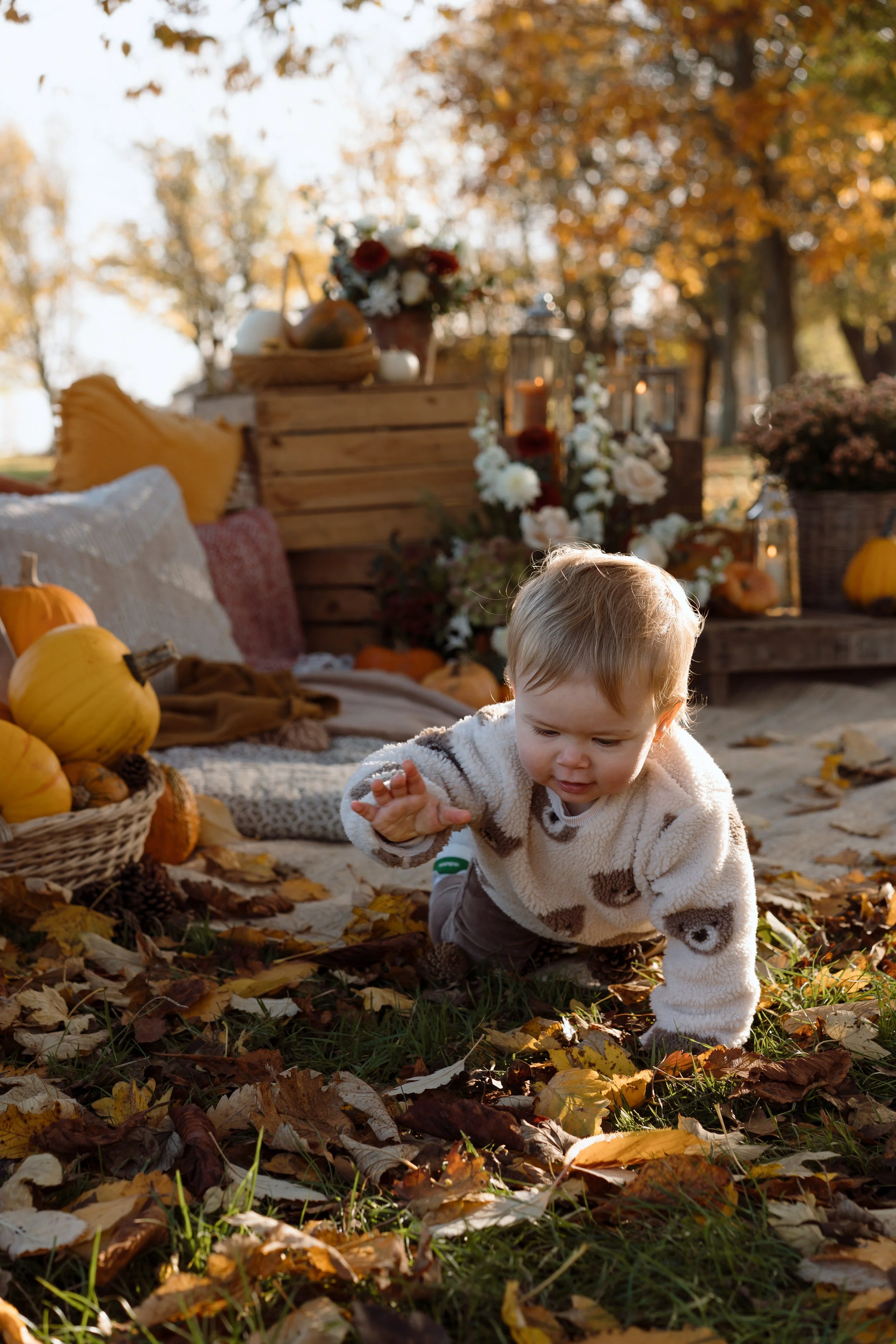 A man with dark hair and a beard holding a baby outside during daylight, with trees and a building in the background.