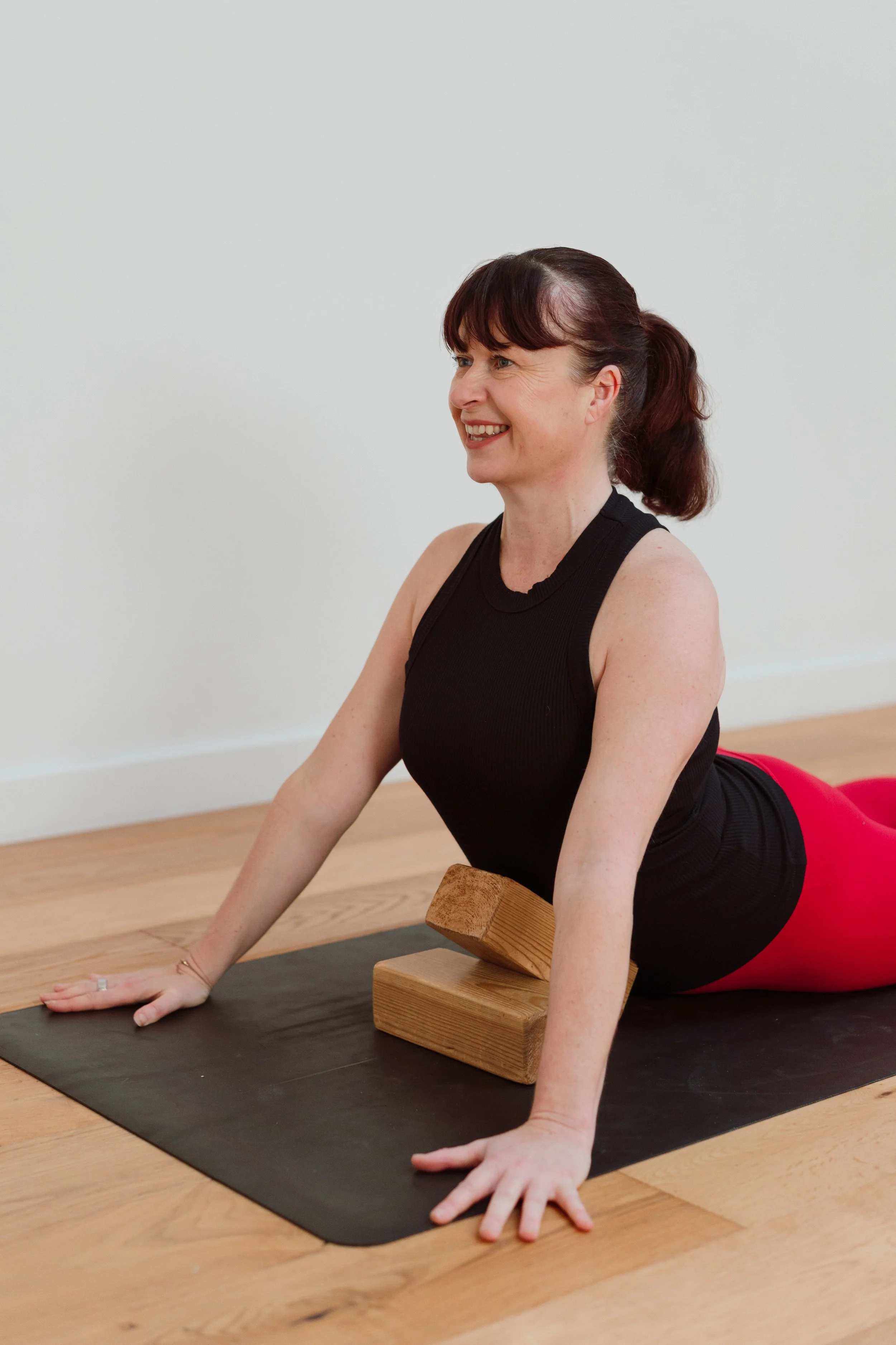 Yoga teacher brand photography by Photography by Trish - woman practising yoga on a mat with a block, natural light studio session, Cambridge, UK