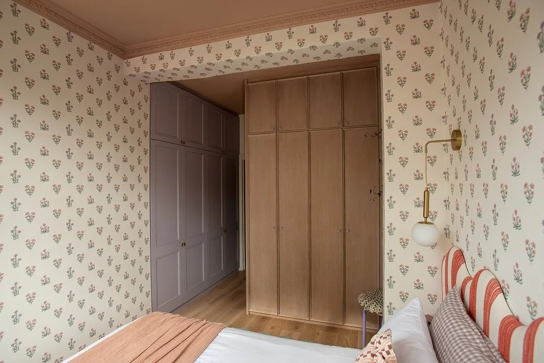 If you&rsquo;re mixing different wardrobes in one room, think about how each finish will balance the other. Here, the painted joinery is paired with a second run in oak, complete with a soft chamfer detail. The lighter timber and lilac handles bring 