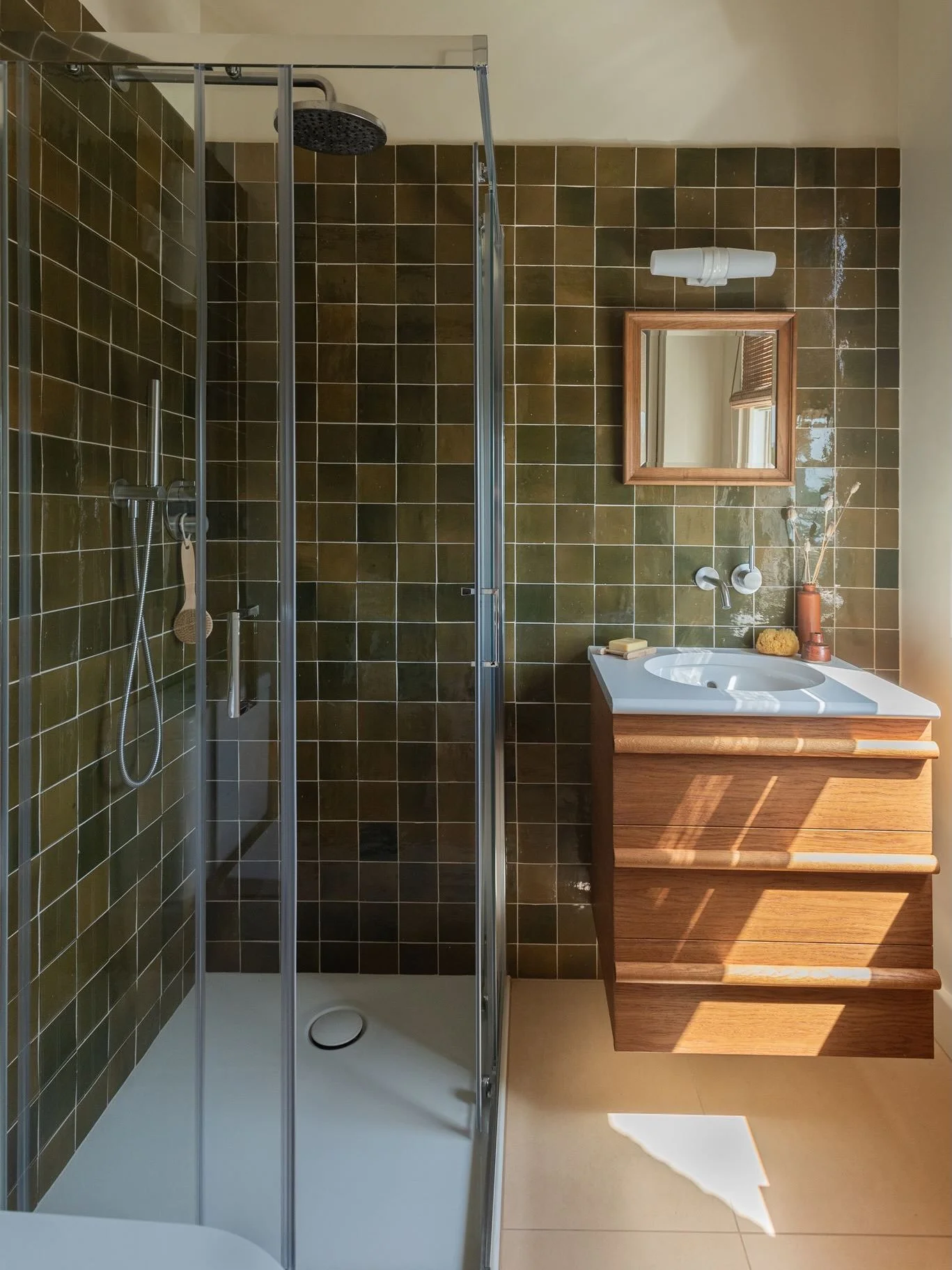 In this Tufnell Park guest en-suite, I colour drenched the paint and carried the olive glazed mosaic tiles from the shower all the way across to the basin wall. 

The beautiful, rich, glossy tone across a wider area creates impact and becomes a major
