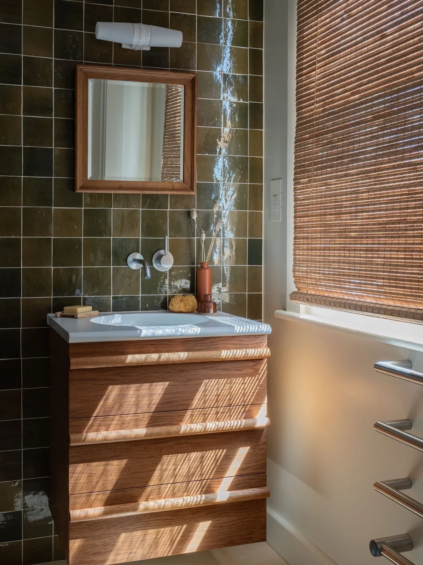 If you want to use deeper colours but you&rsquo;re worried your space might look too dark or gloomy, consider the finish of the tile. 
In this bathroom, I chose these deep olive tiles with a beautiful, glazed finish. The slight variation and sheen ca