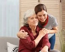 Two women, one elderly, and one younger embracing with a smile