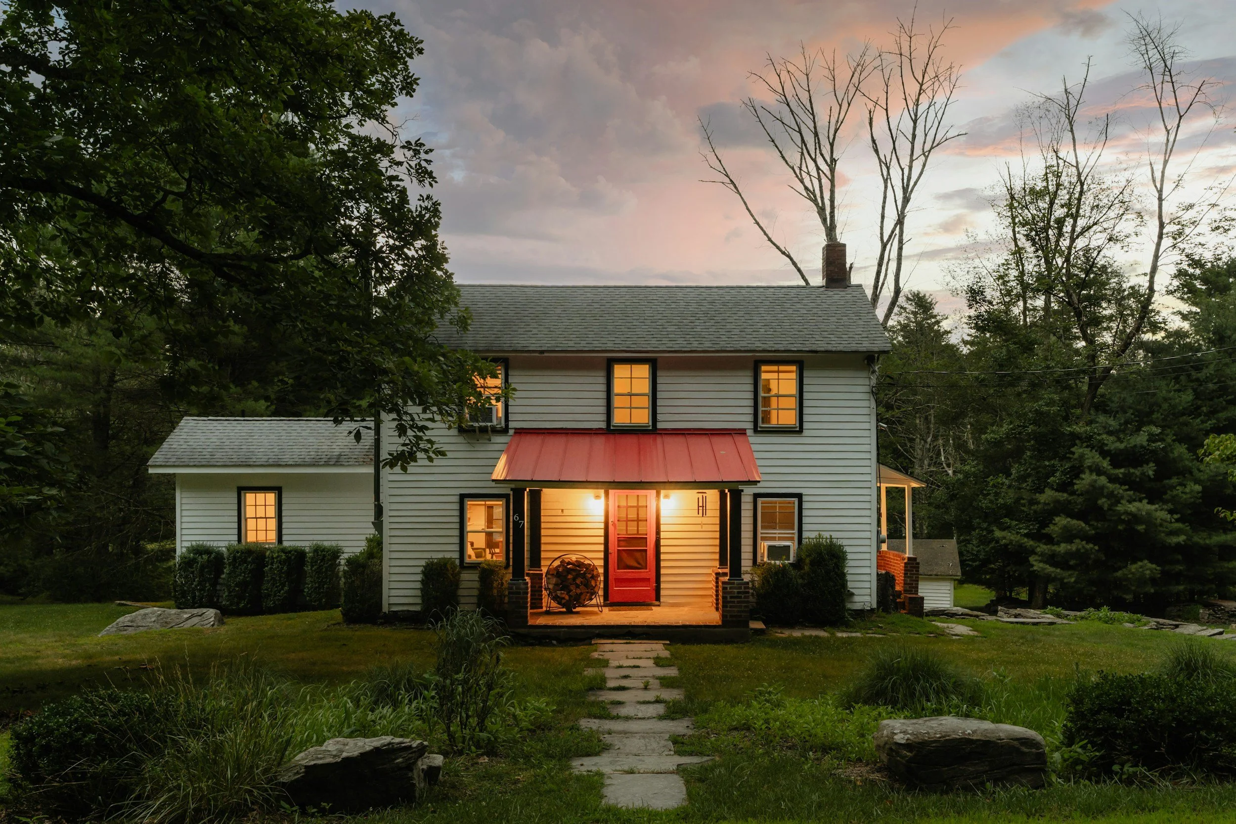 two story single family home at dusk with porch lights on. h