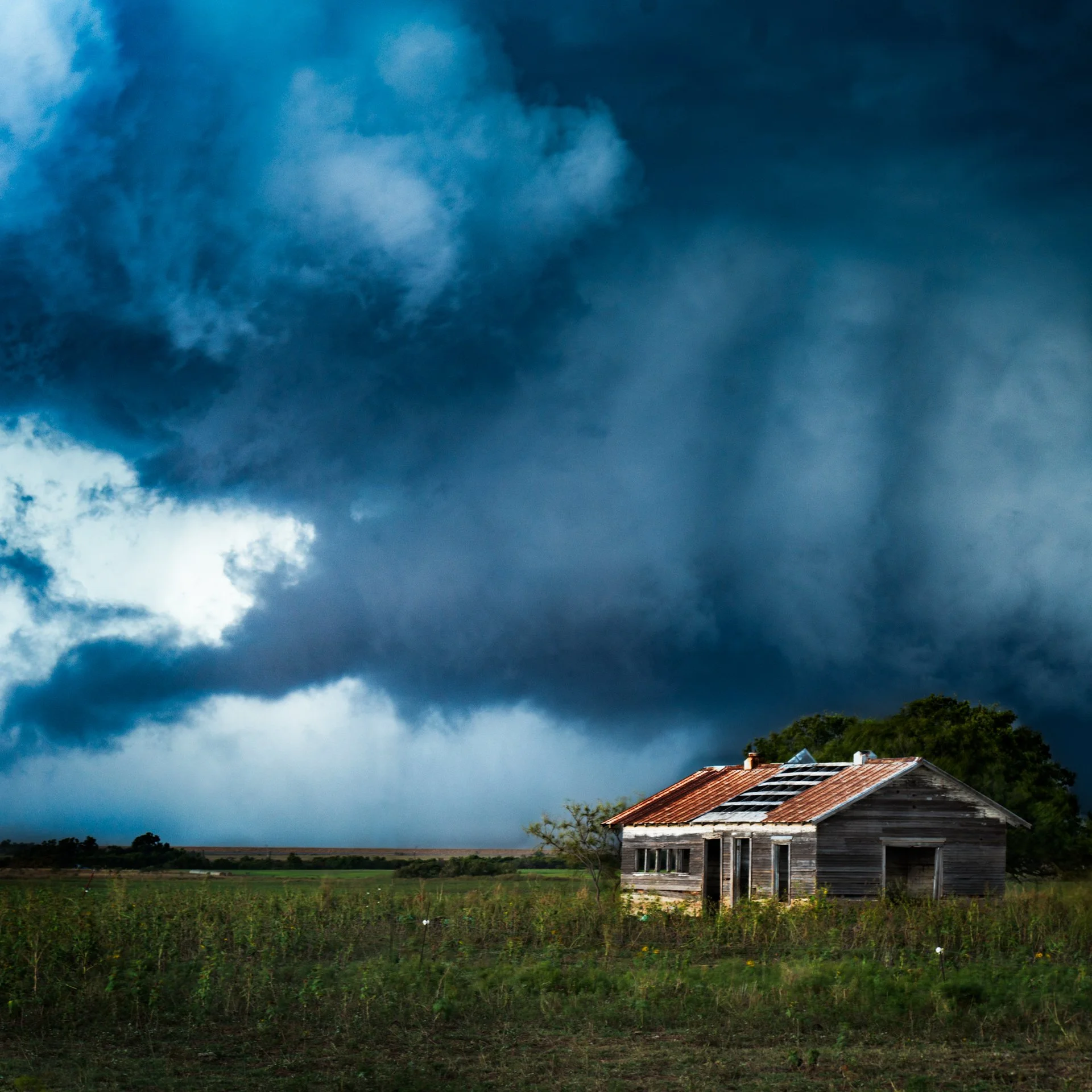A lonely abandoned house in West Oklahoma dwarfed by a large wallcloud in the background.