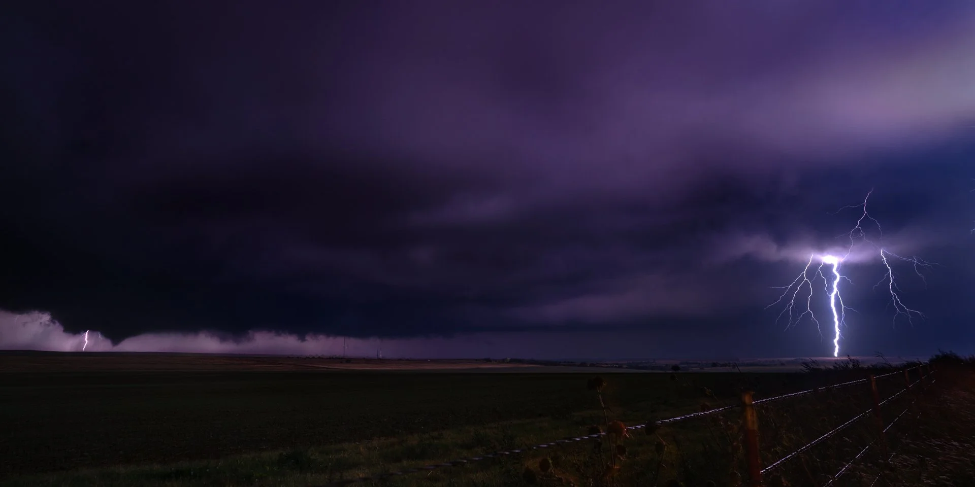 A night time tornado is revealed by a couple of large lightning strikes.