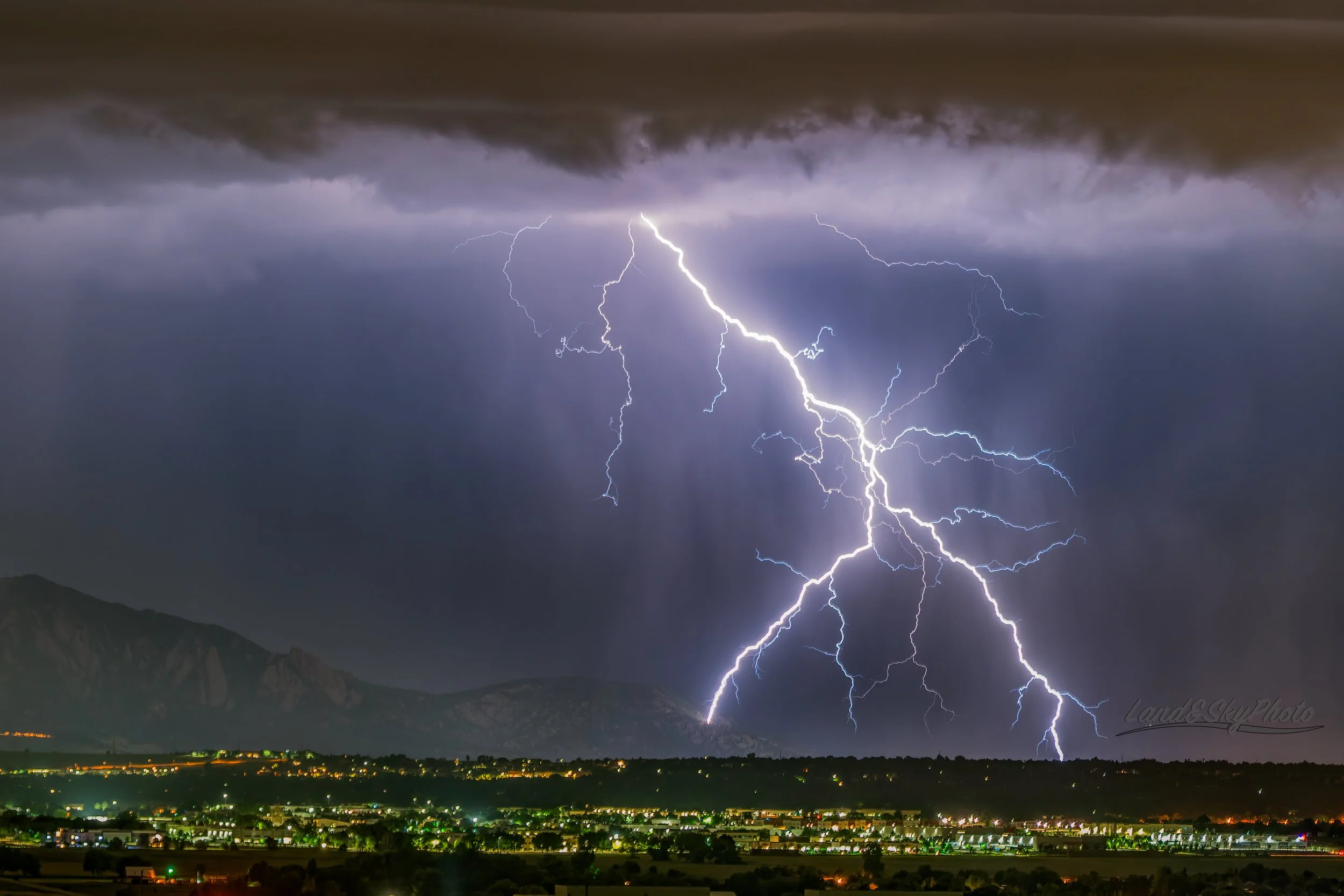 A large forking lightning bolt strikes the Flatirons near Boulder, Colorado