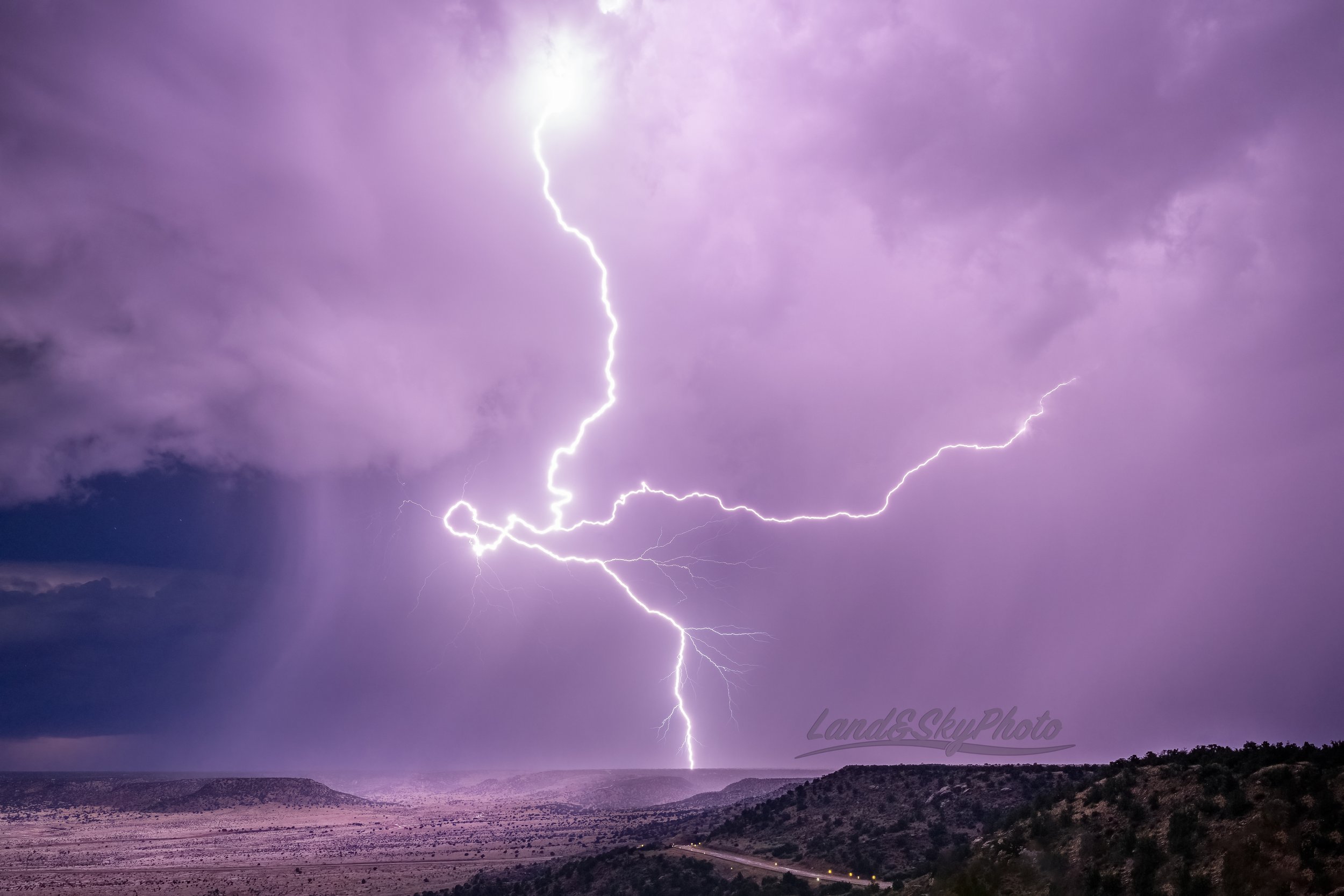 A writhing and twisting lightning bolt strikes the plateaus near House, New Mexico.