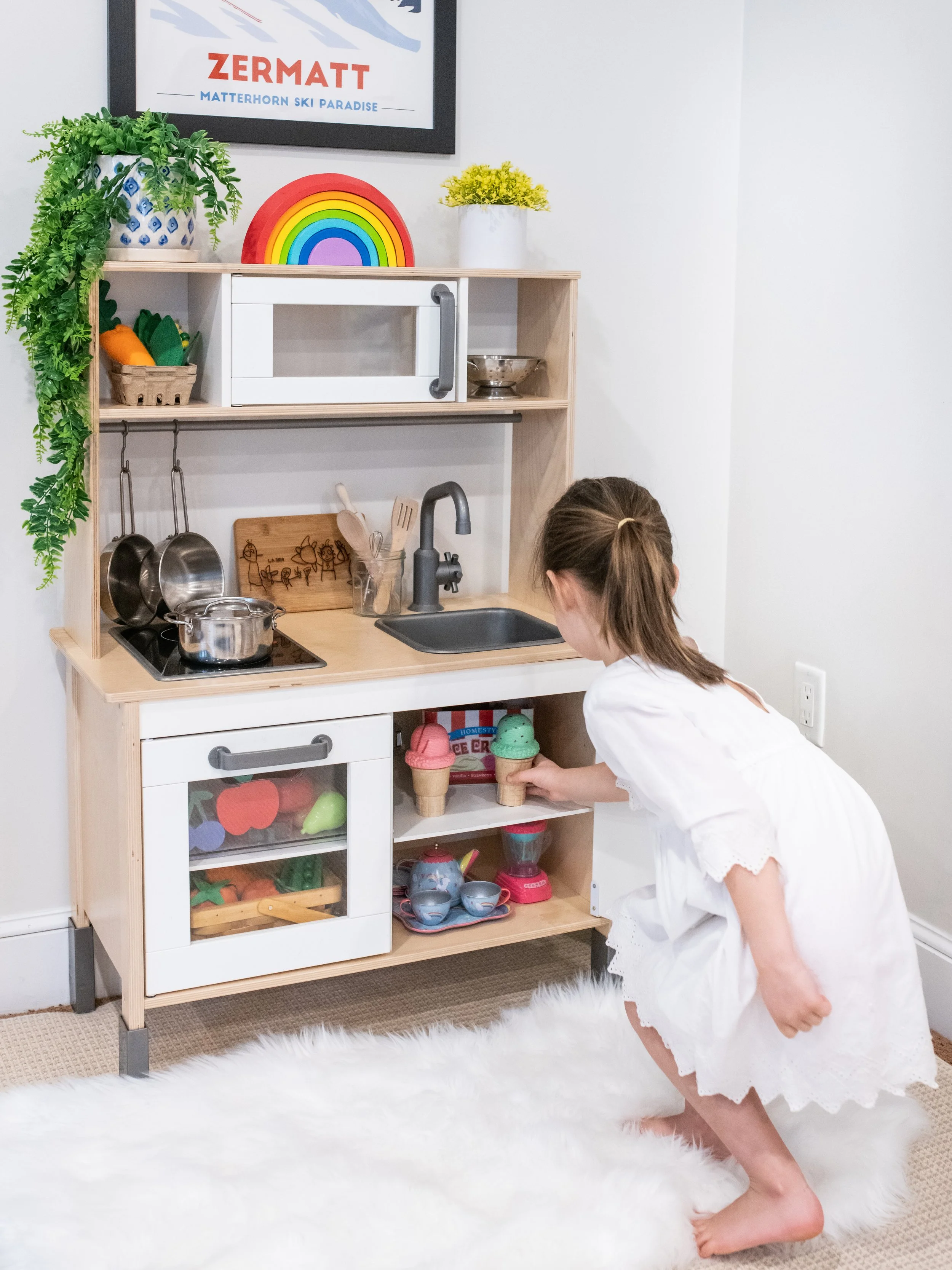 A child looking at a play kitchen in a playroom.