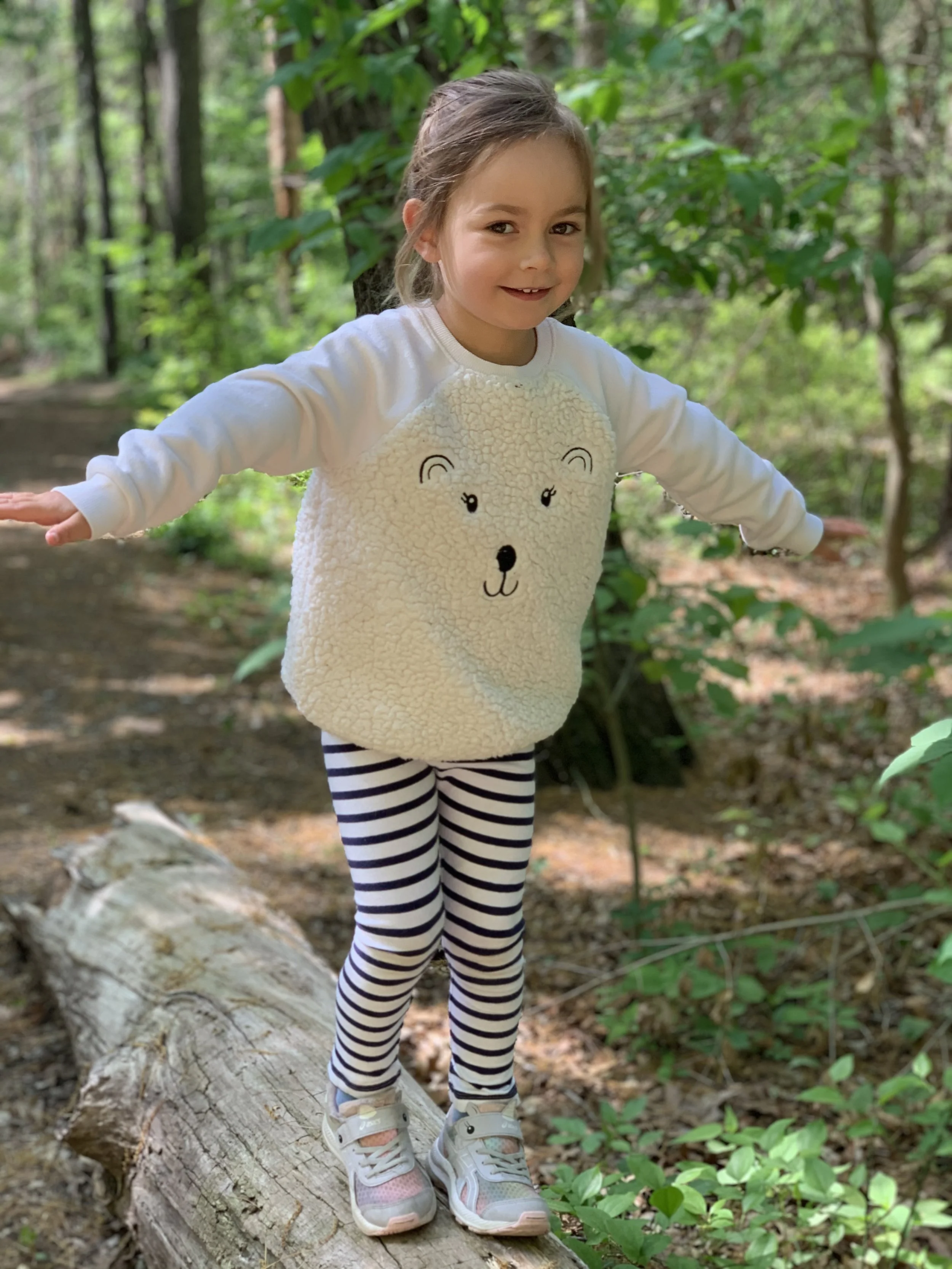 Child balancing outdoors on a log, playing.