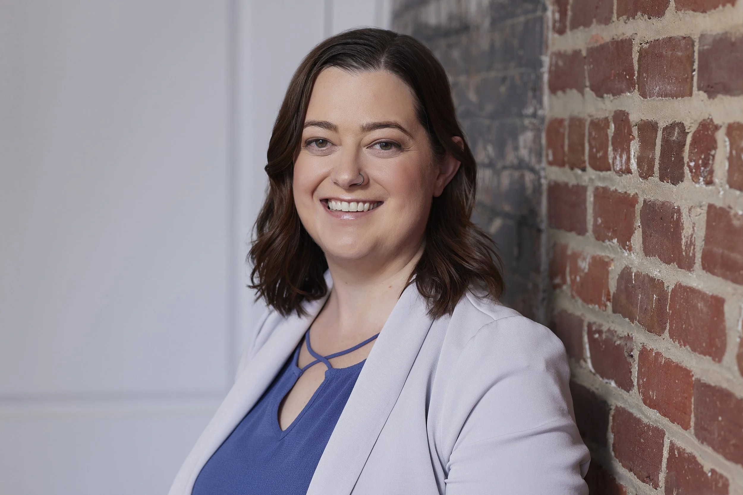 Woman standing by brick wall smiling. You may be looking for anxiety treatment in Duluth, Georgia. Look no further for a Georgia anxiety therapist, Georgia chronic illness therapist, or therapist for people pleasing or burnout.