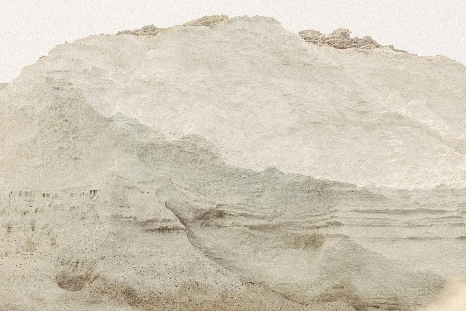 A large ice or snow formation with layered textures, possibly a glacier, with some rocky and gravelly areas at the top.