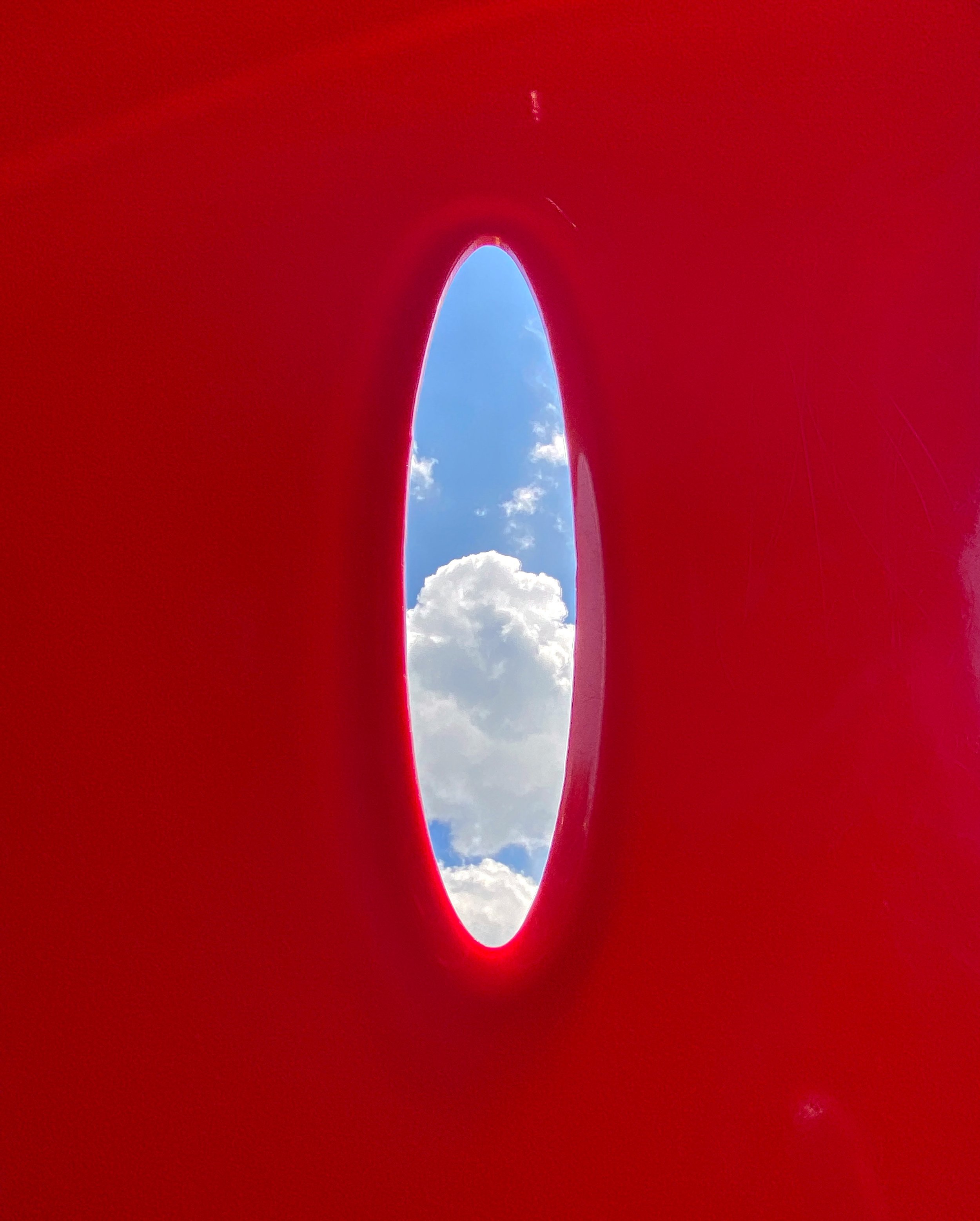 An image of the sky looking through a hole in a child's playground slide. 