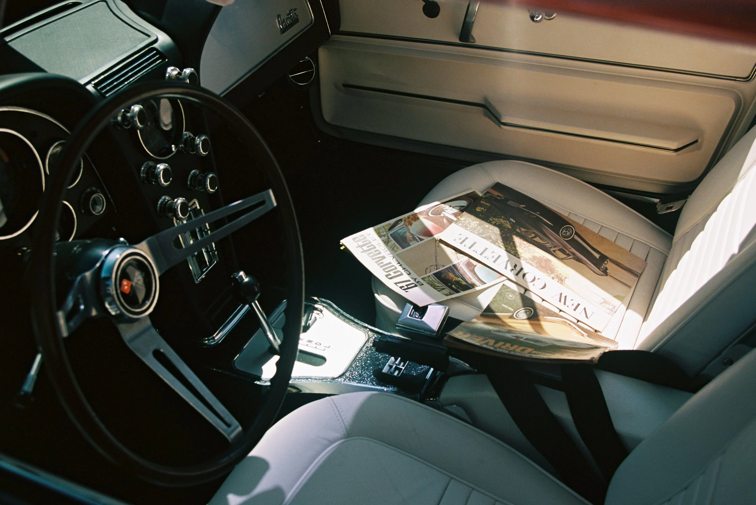 Interior film photo of a classic car with a magazine on the seat.