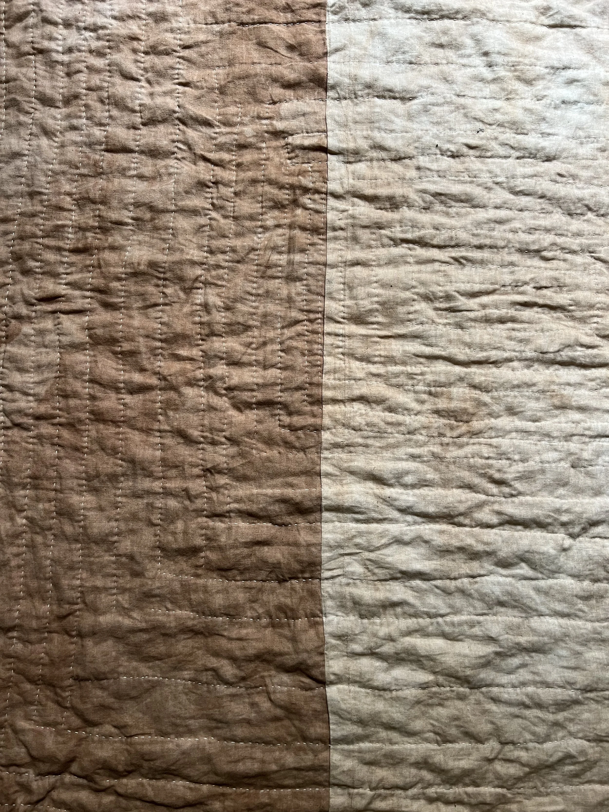 Close-up of a brown and beige textured fabric with visible stitching and wrinkles.