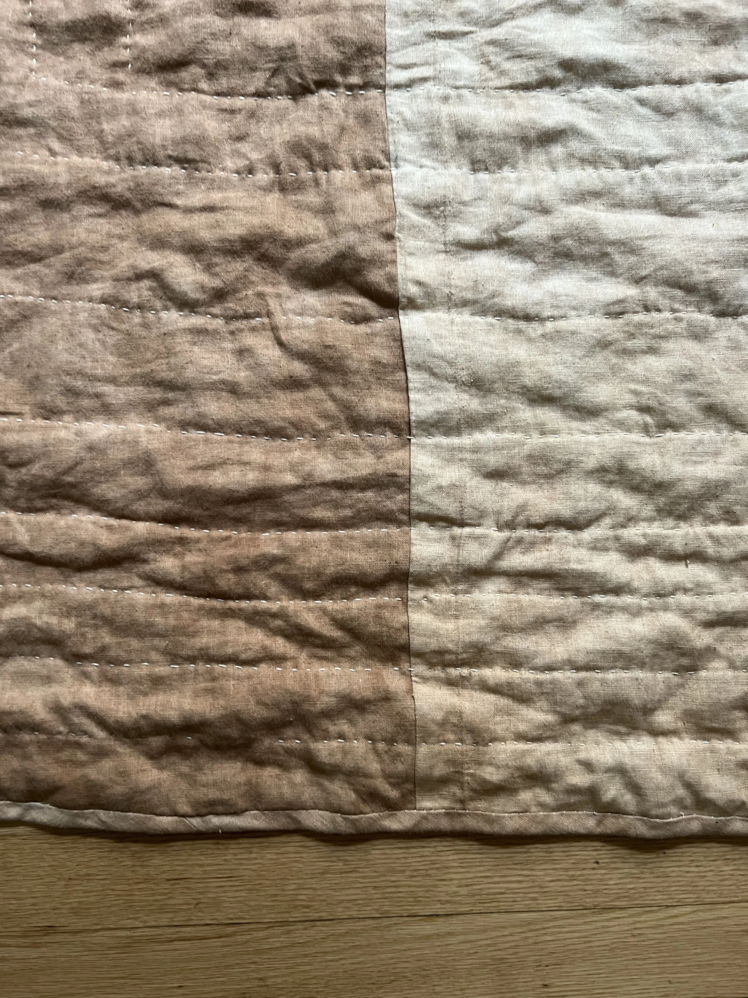Close-up of a quilt with brown and beige fabric panels, featuring visible stitching lines.
