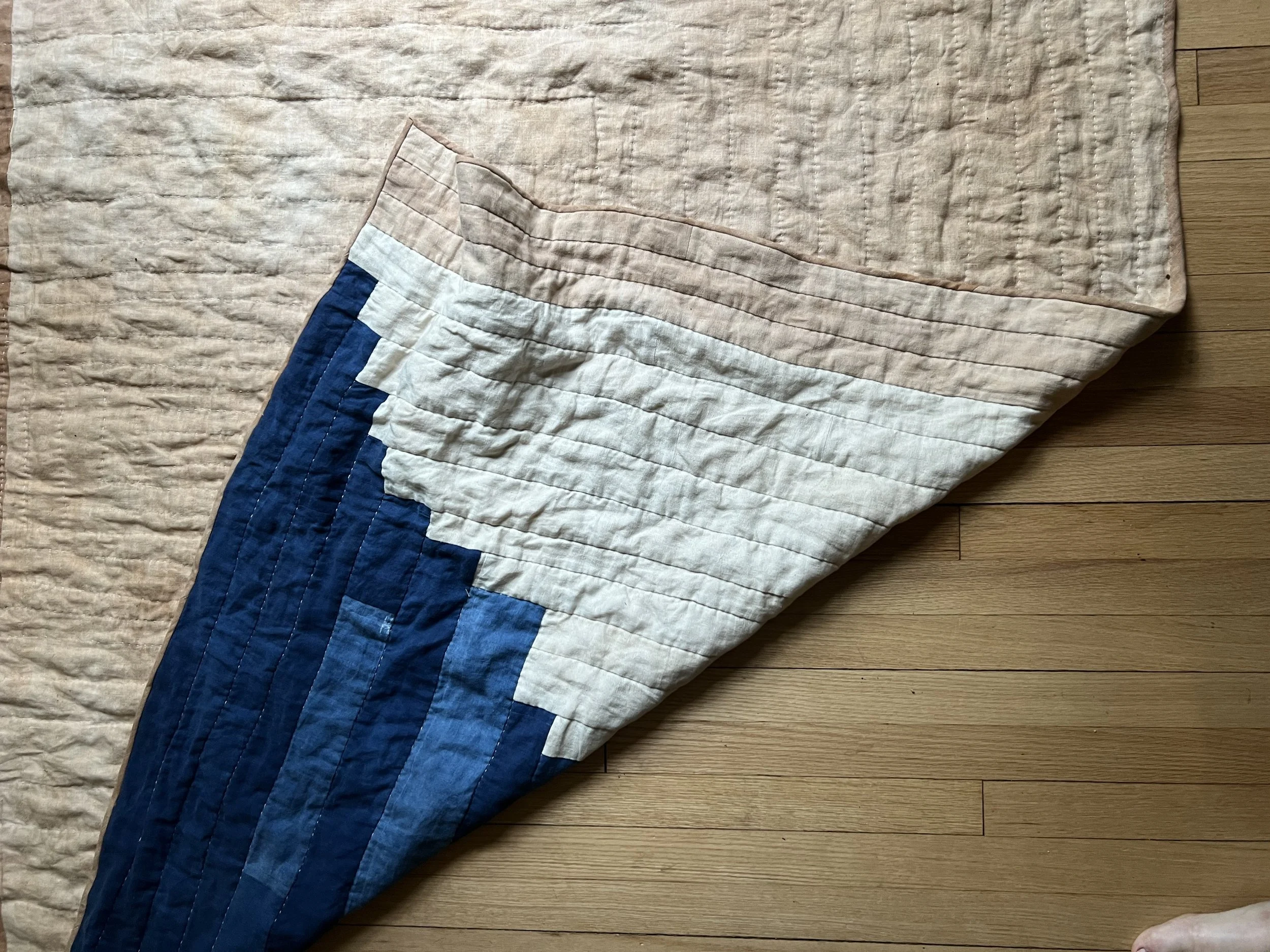 Patchwork quilt with blue and beige fabric on wooden floor