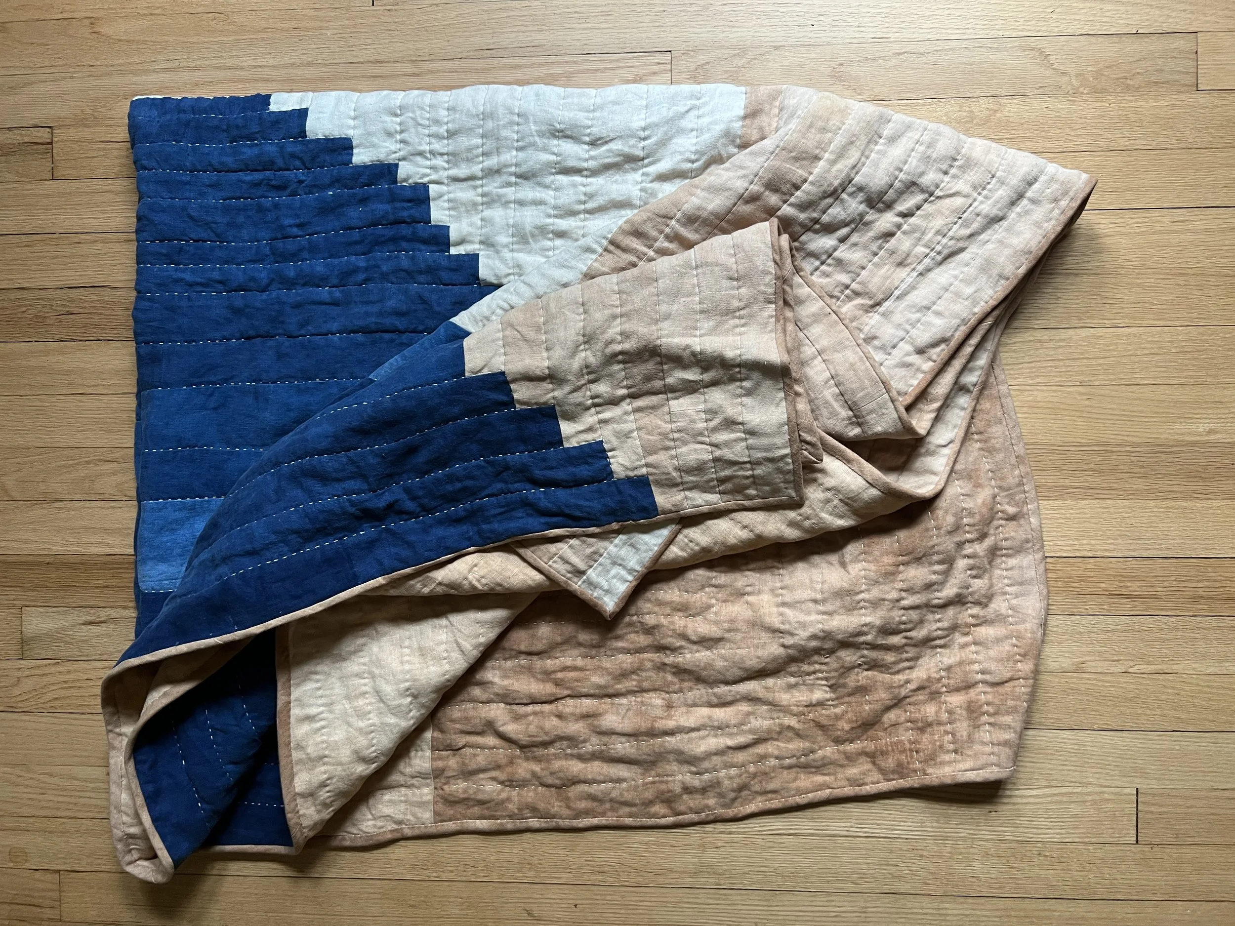 Folded quilt with blue and beige geometric pattern on wooden floor