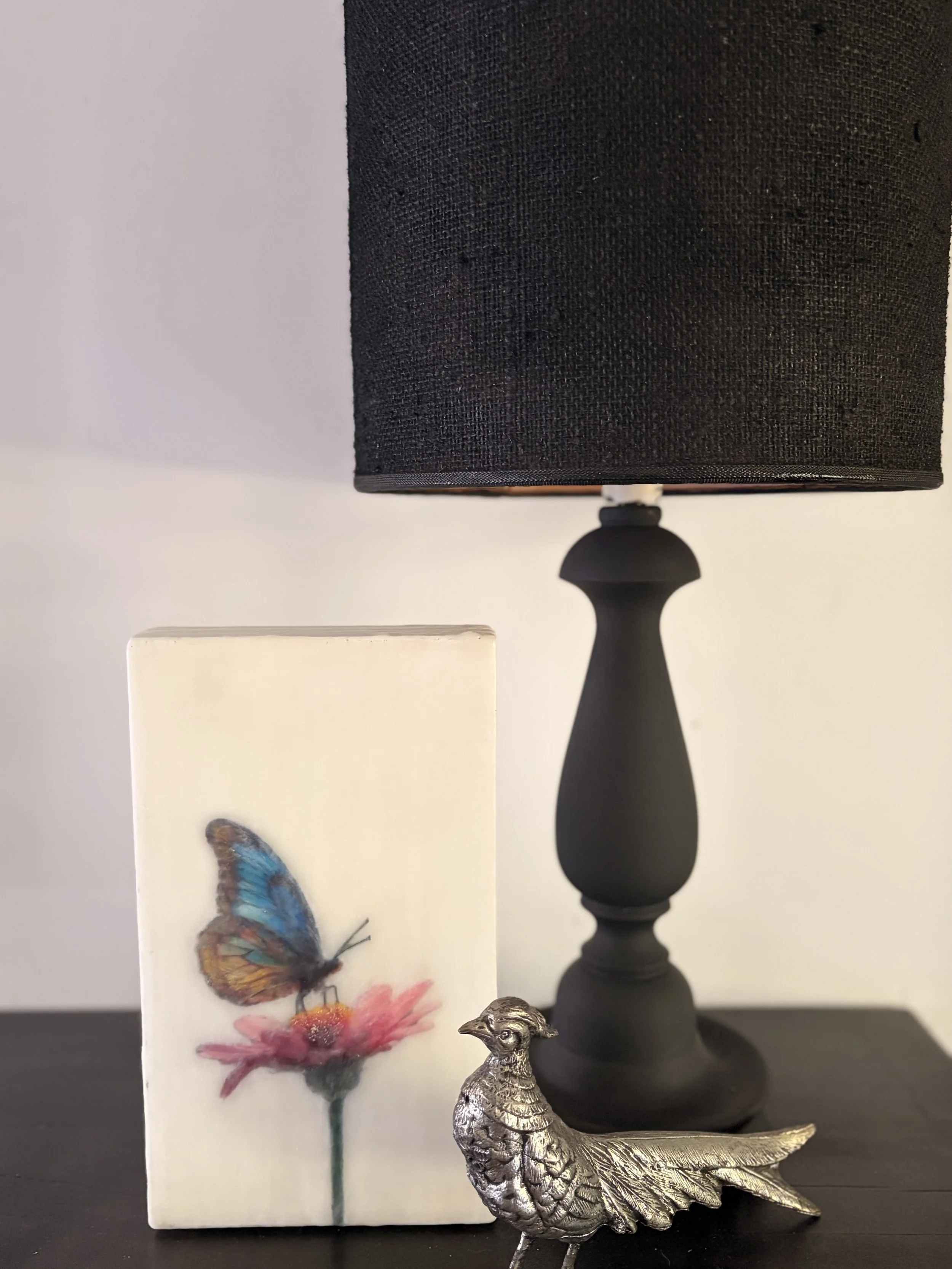 A blue and gold butterfly resting on a pink flower, rendered in luminous encaustic wax and mixed media with a dreamy, ethereal finish.