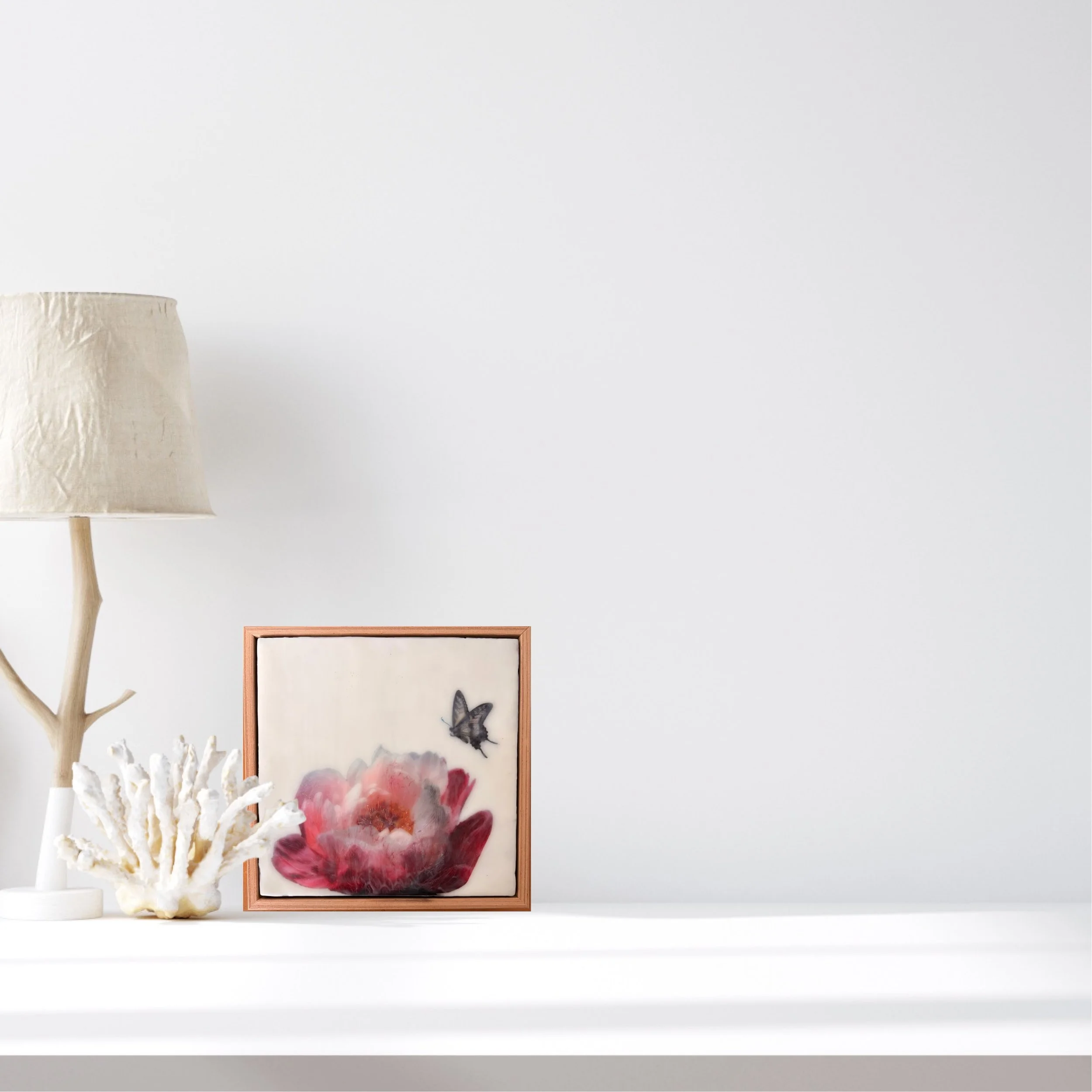 Encaustic wax artwork of a soft pink and crimson flower with a butterfly hovering above, featuring layered wax textures and a gentle, dreamlike finish.