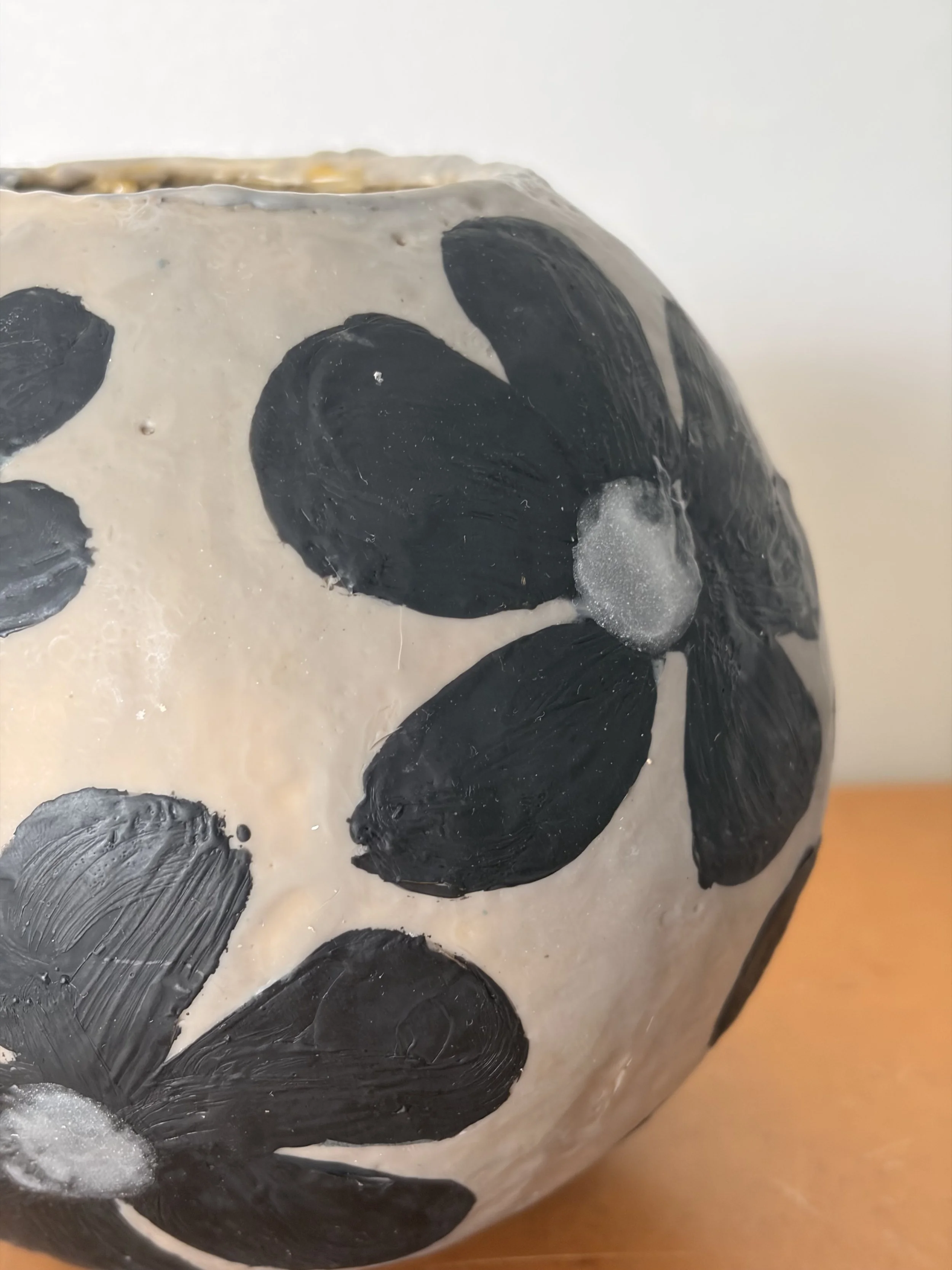 Small round encaustic wax artwork featuring dark floral forms and textured layers in black and earthy tones, titled Black Daisies.