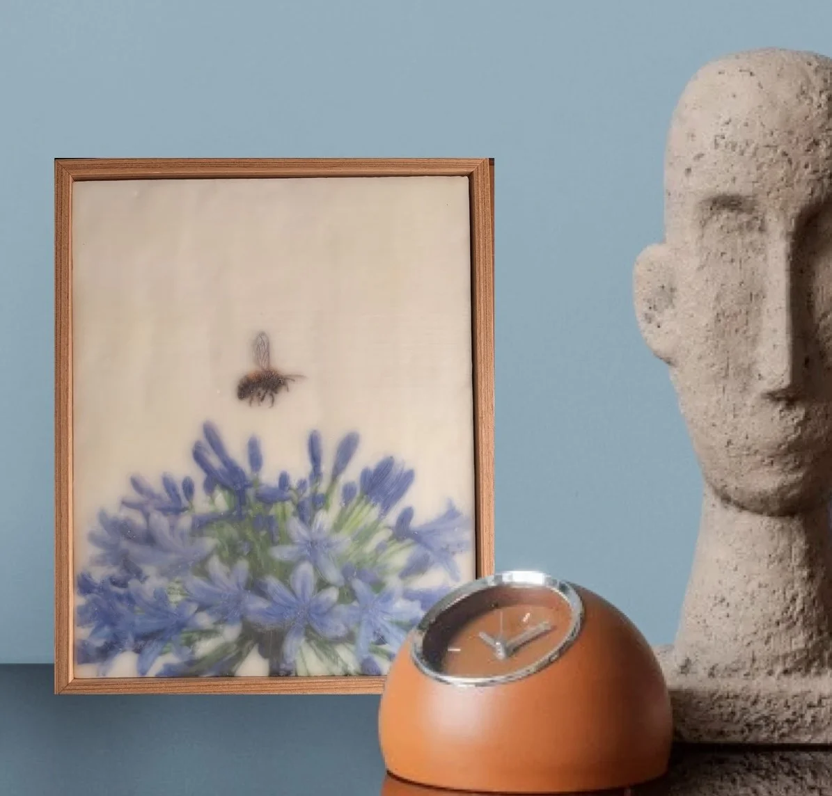 Original encaustic wax artwork featuring a softly rendered honeybee hovering above vibrant blue agapanthus flowers. Dreamy botanical artwork with luminous beeswax layers, framed