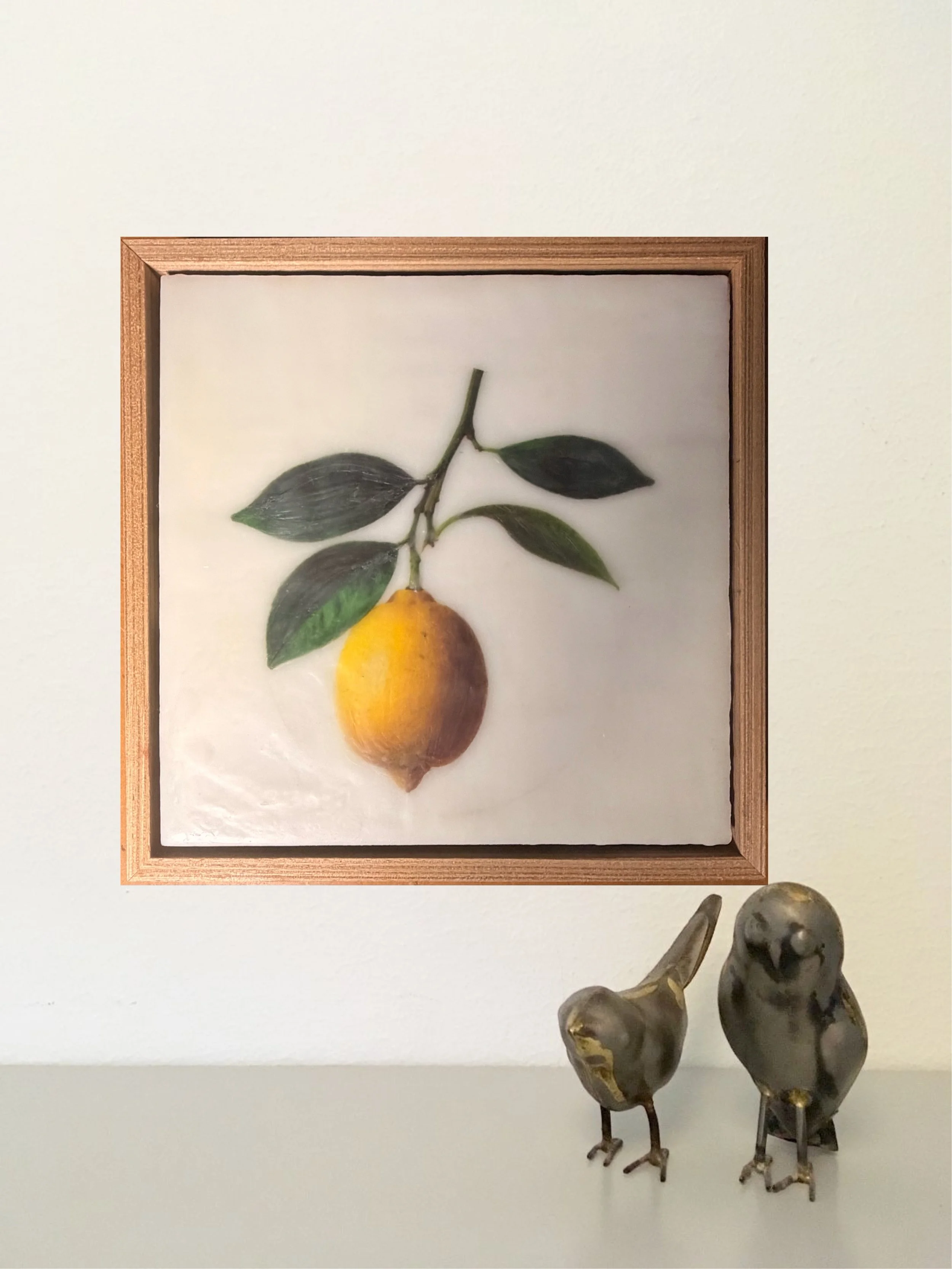 Minimalist encaustic wax botanical artwork featuring a single yellow lemon hanging from a leafy branch on a luminous white background in a timber floating frame by Australian artist Karen Canning.