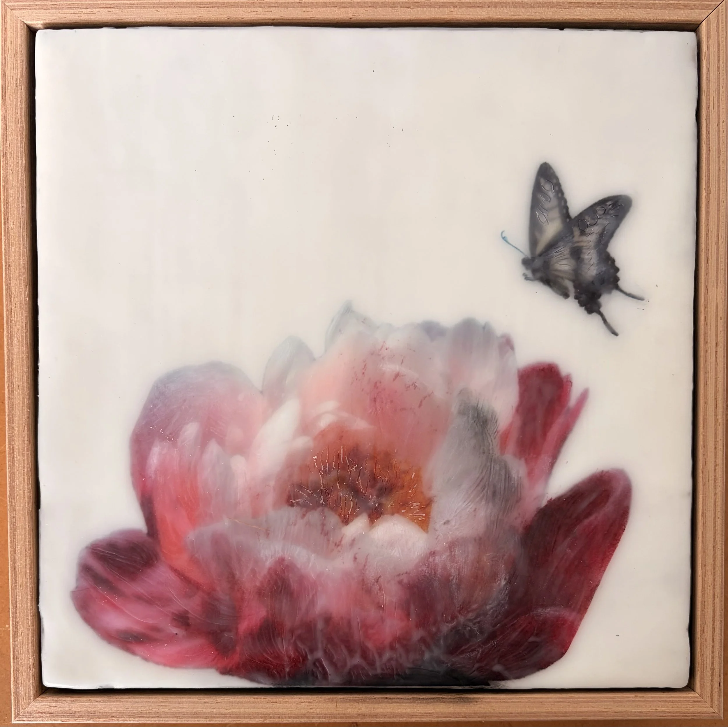 Encaustic wax artwork of a soft pink and crimson flower with a butterfly hovering above, featuring layered wax textures and a gentle, dreamlike finish.