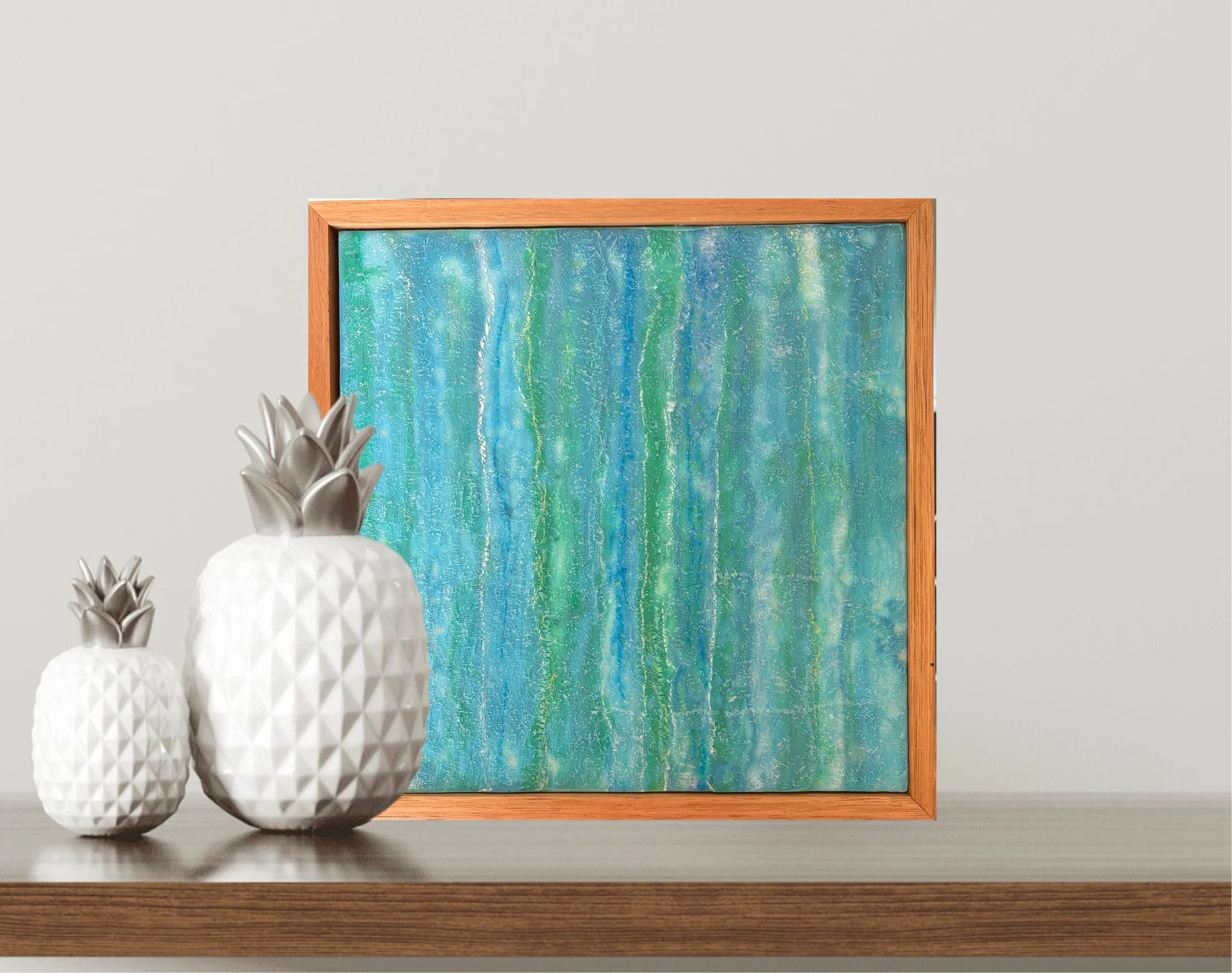 “A square 30 x 30cm encaustic wax and mixed media artwork featuring layered blue and green abstract textures, framed in natural timber.”