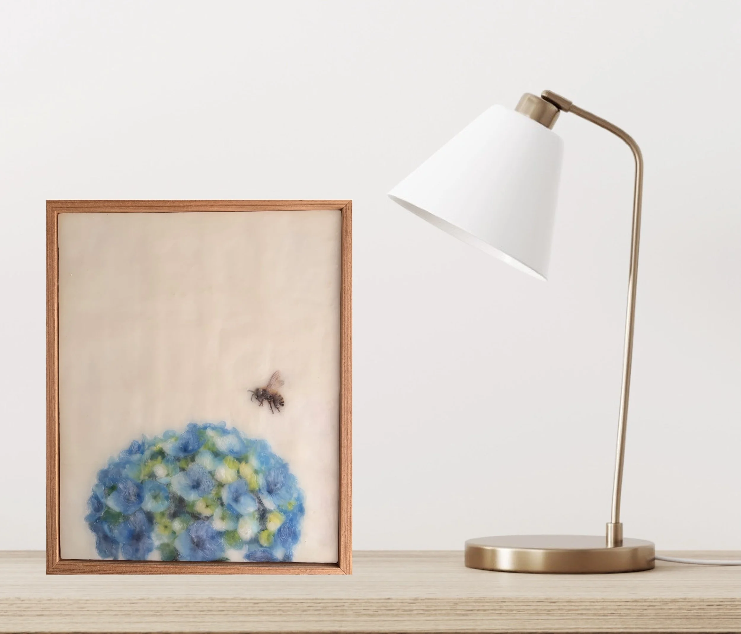 Original encaustic wax artwork featuring a honeybee hovering above blue hydrangea flowers, framed in Tasmanian oak with soft translucent beeswax layers.