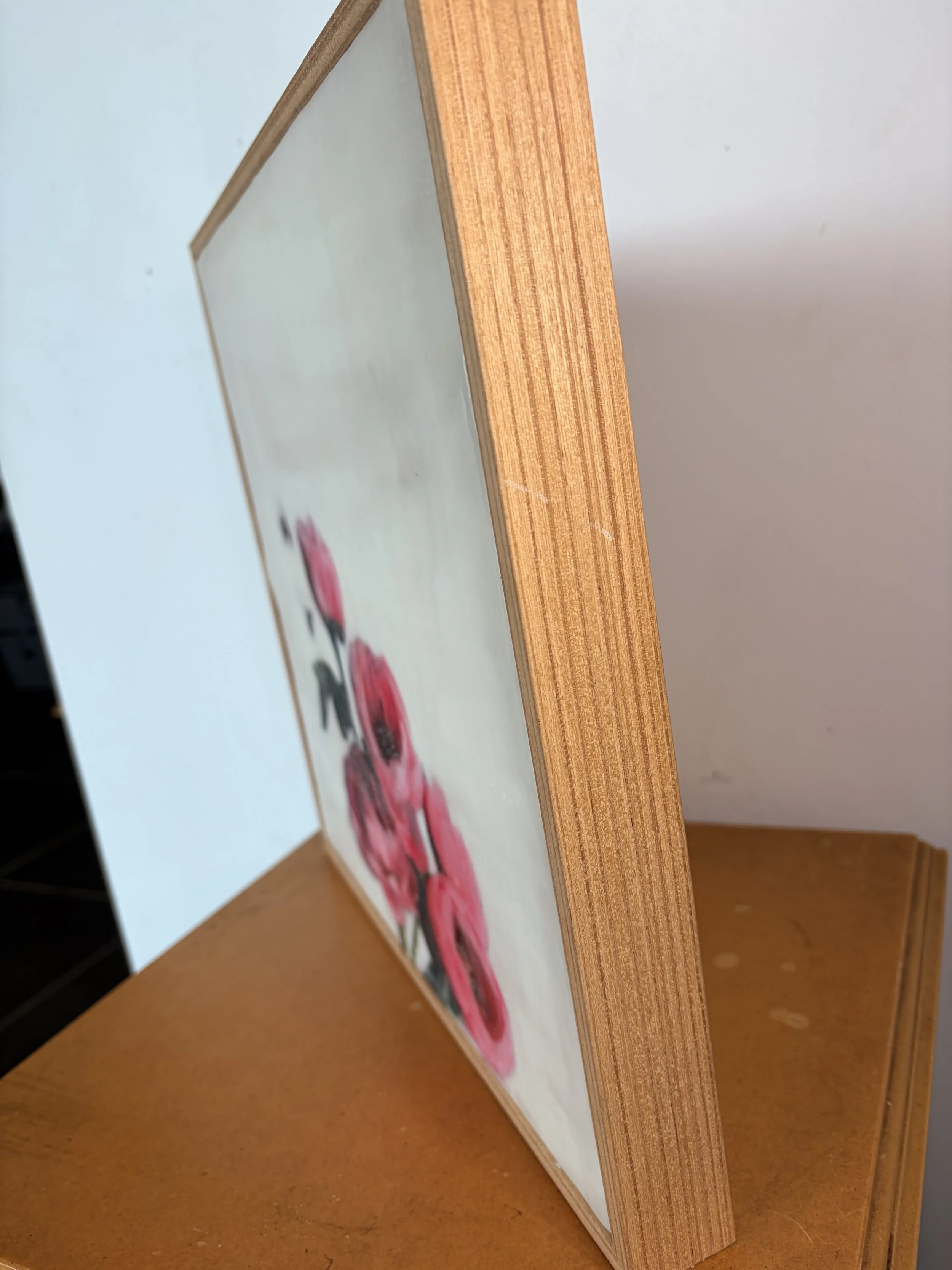 an encaustic wax/mixed media artwork of soft pink flowers and two bees