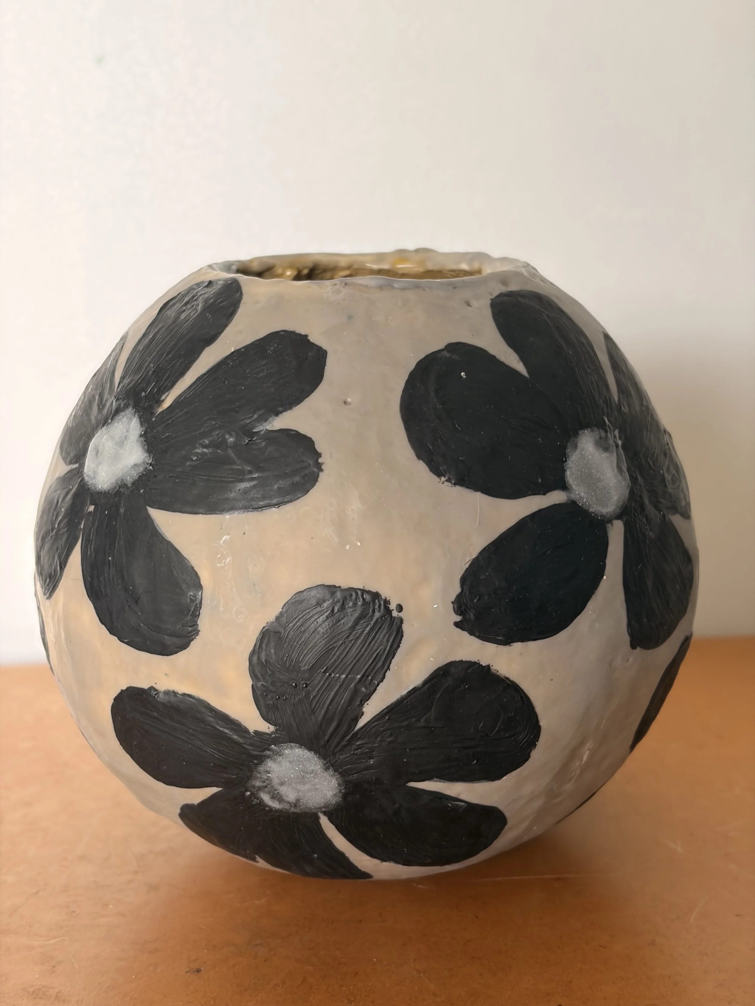 Small round encaustic wax artwork featuring dark floral forms and textured layers in black and earthy tones, titled Black Daisies.
