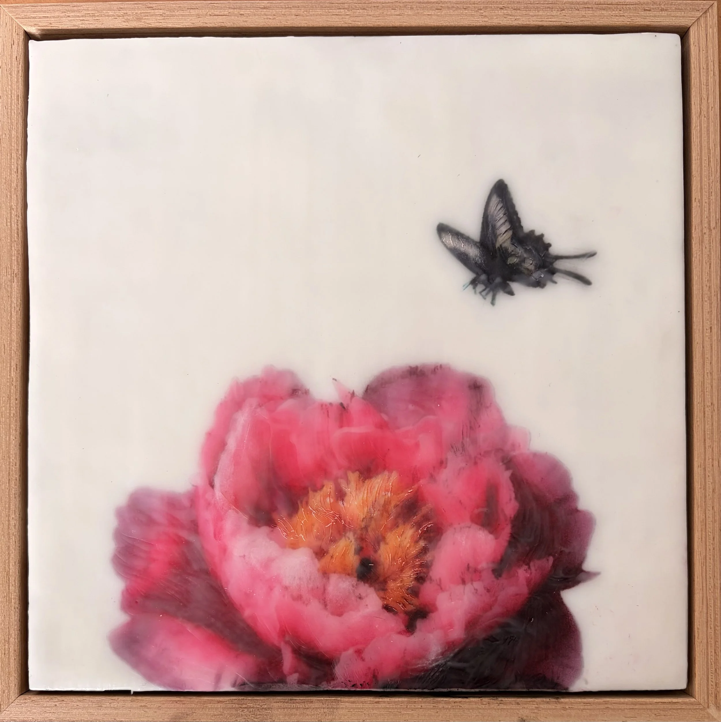 Encaustic wax artwork of a soft pink flower with a delicate butterfly hovering above, created with layered wax textures and gentle blended tones.