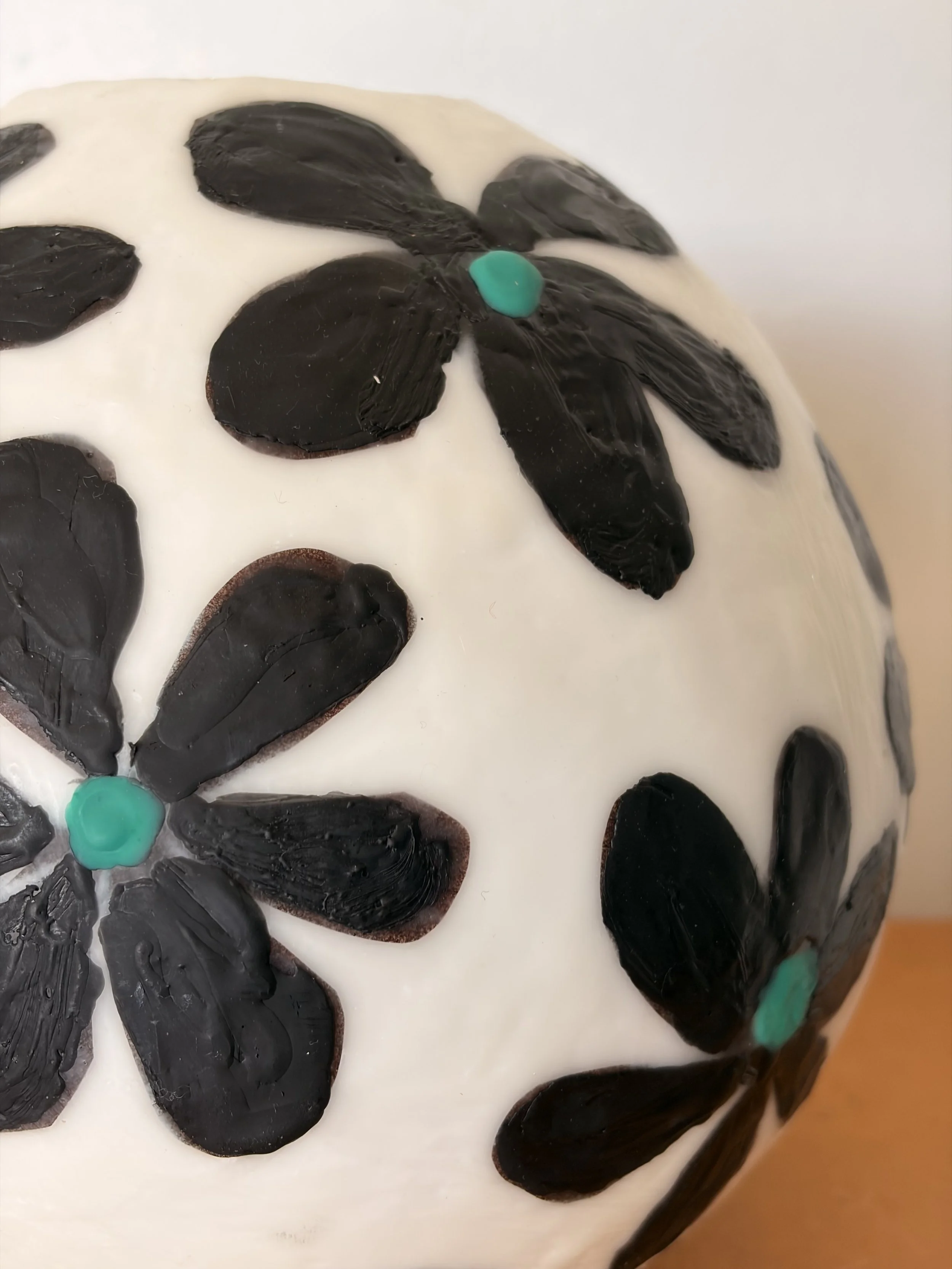 Handmade encaustic wax bowl featuring black floral motifs on a white rounded form, created by artist Karen Canning.
