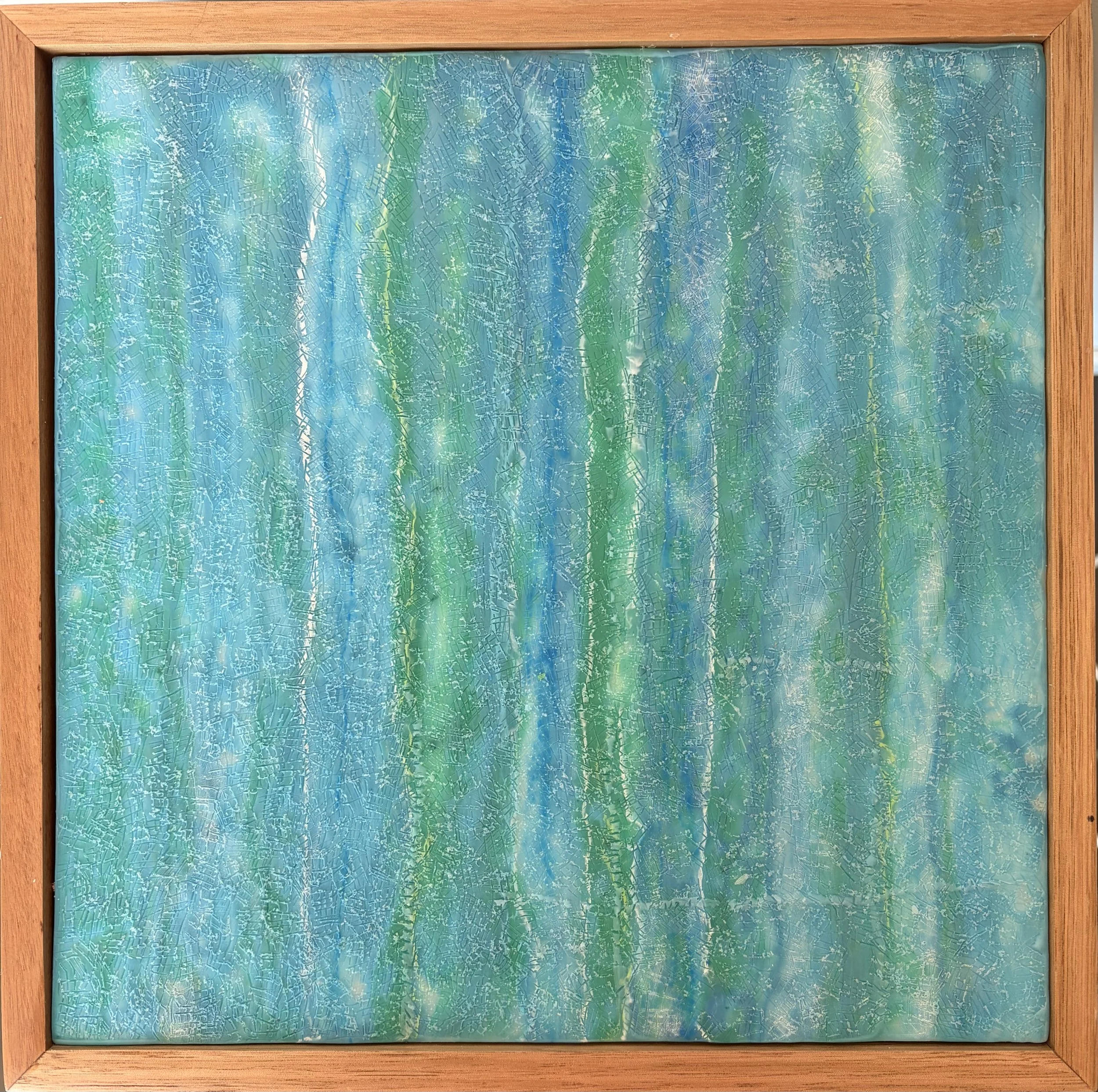 “A square 30 x 30cm encaustic wax and mixed media artwork featuring layered blue and green abstract textures, framed in natural timber.”