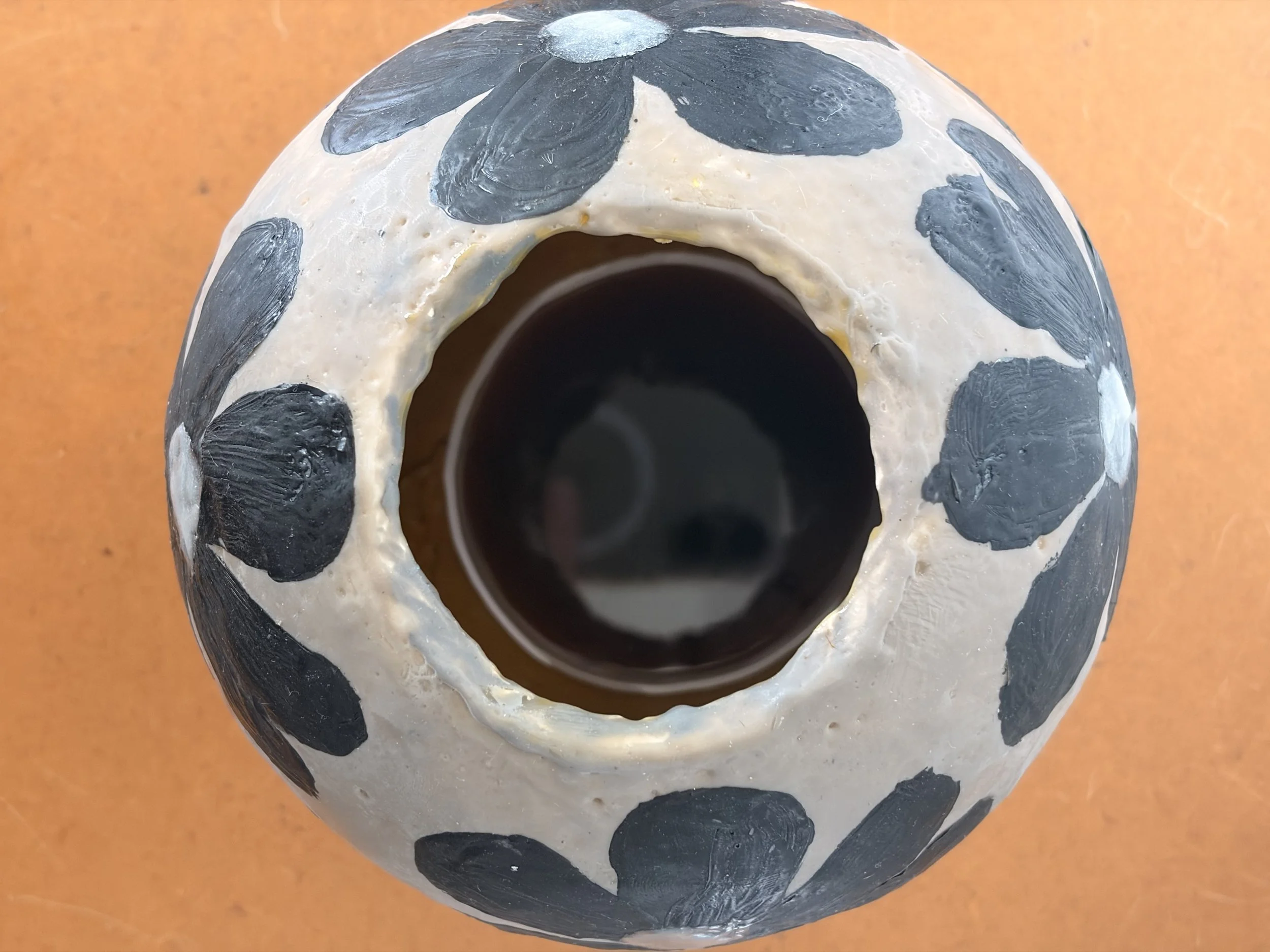 Small round encaustic wax artwork featuring dark floral forms and textured layers in black and earthy tones, titled Black Daisies.