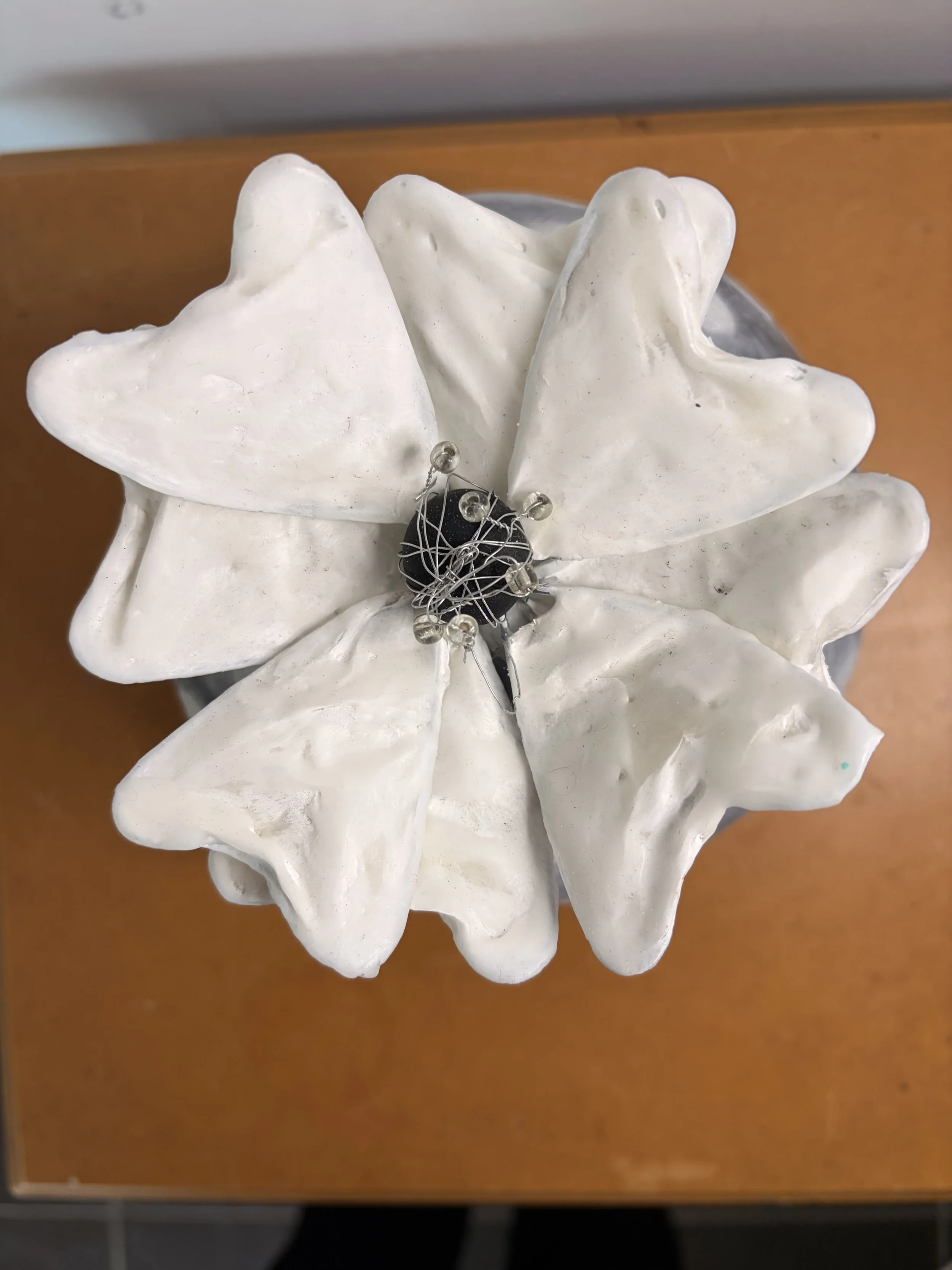 Encaustic wax and mixed media sculpture featuring a round grey textured form with raised white floral patterns and a sculptural white flower on top, displayed as a decorative art object.