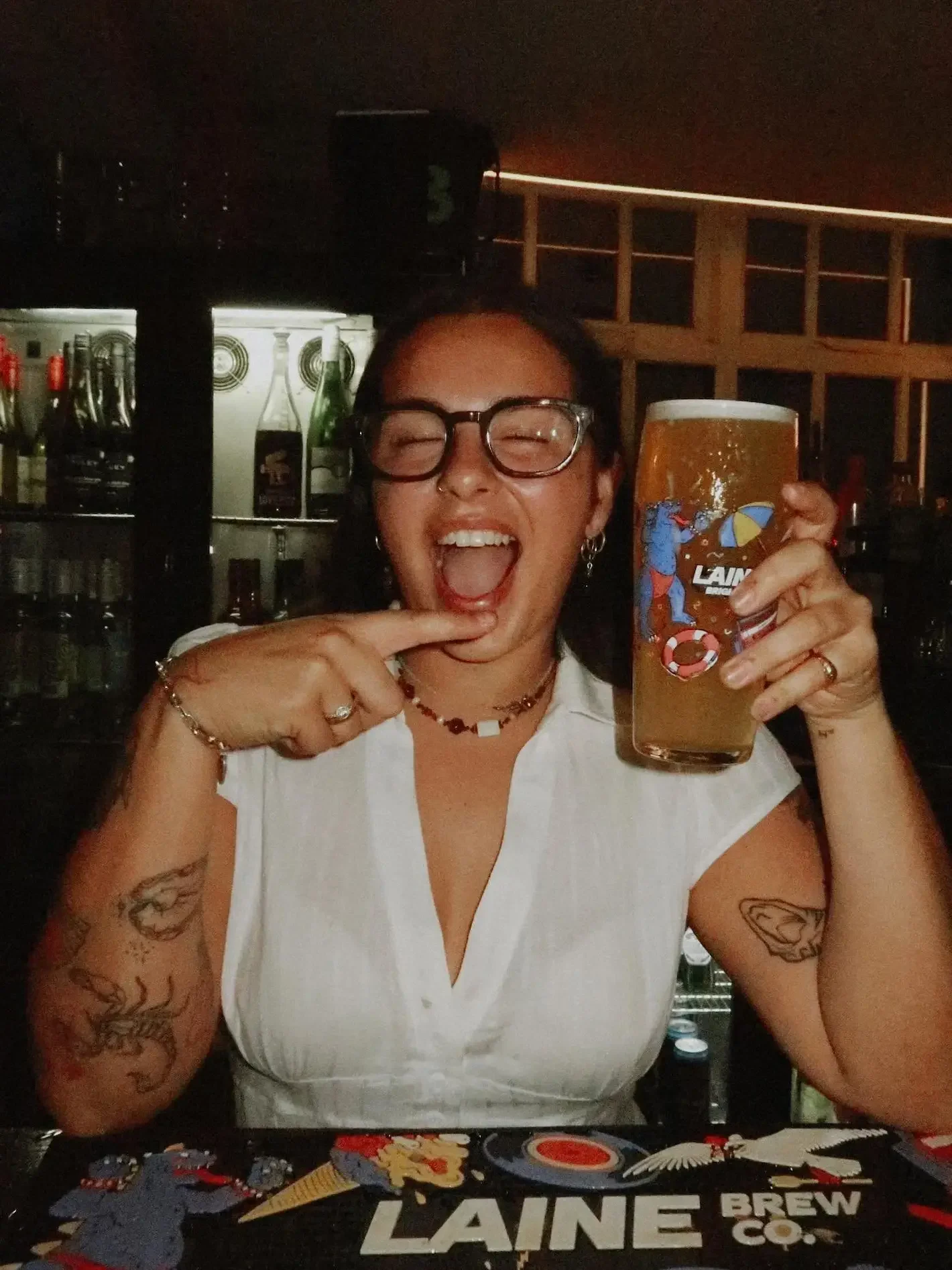 Guest holding a pint of Laine beer at the bar at Oculist Brighton.