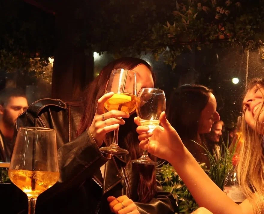 People clinking wine glasses on the Oculisty Brighton roof terrace.