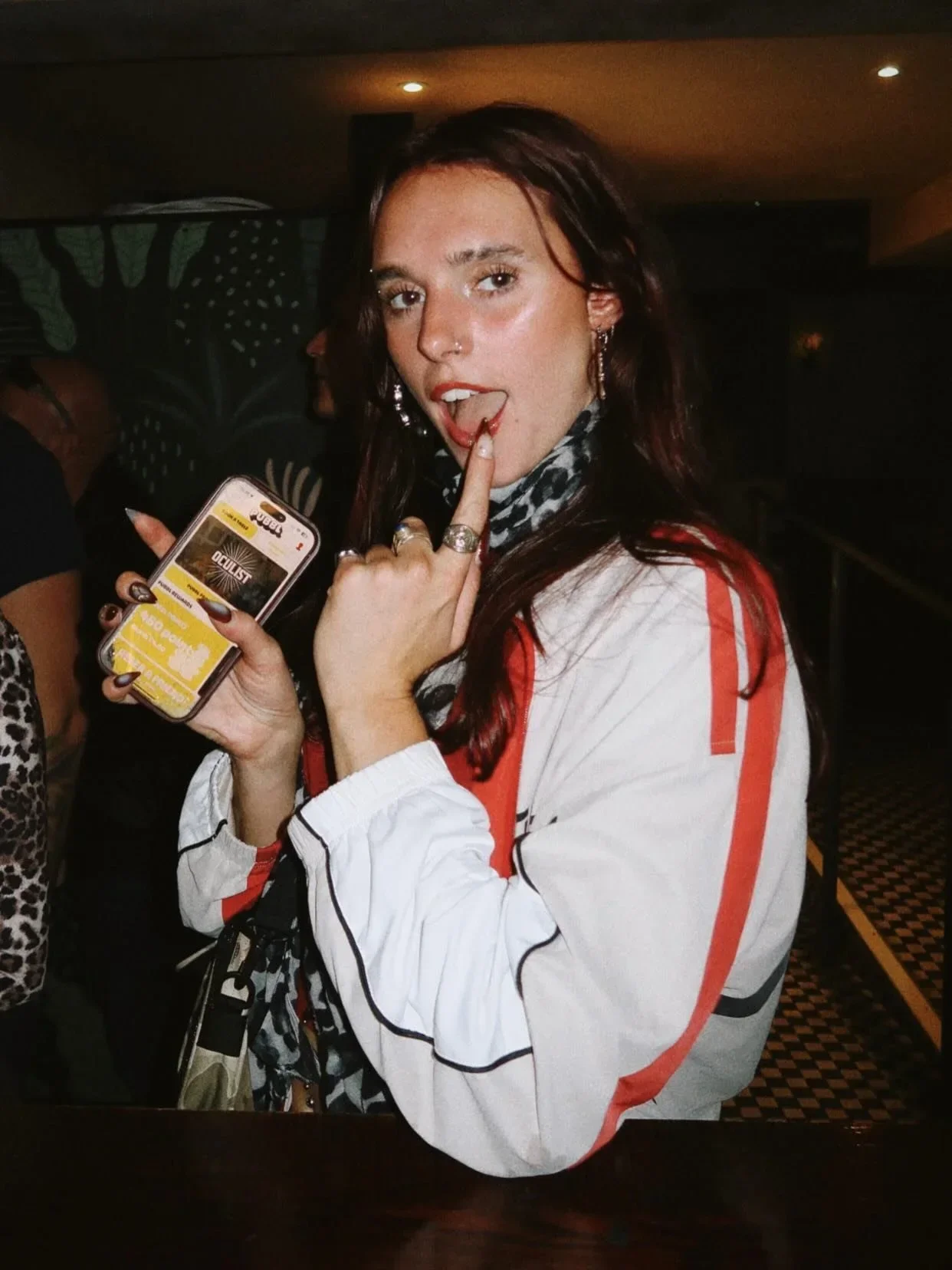 Guest holding a phone with drinks deals during a student night at Oculist Brighton.