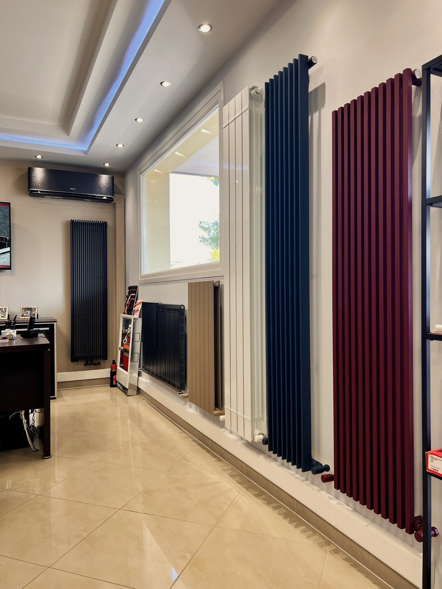 Interior view of the Tsolakidis showroom featuring a wide selection of modern decorative radiators, including vertical heating panels, mirror-style radiators, and colored designer units