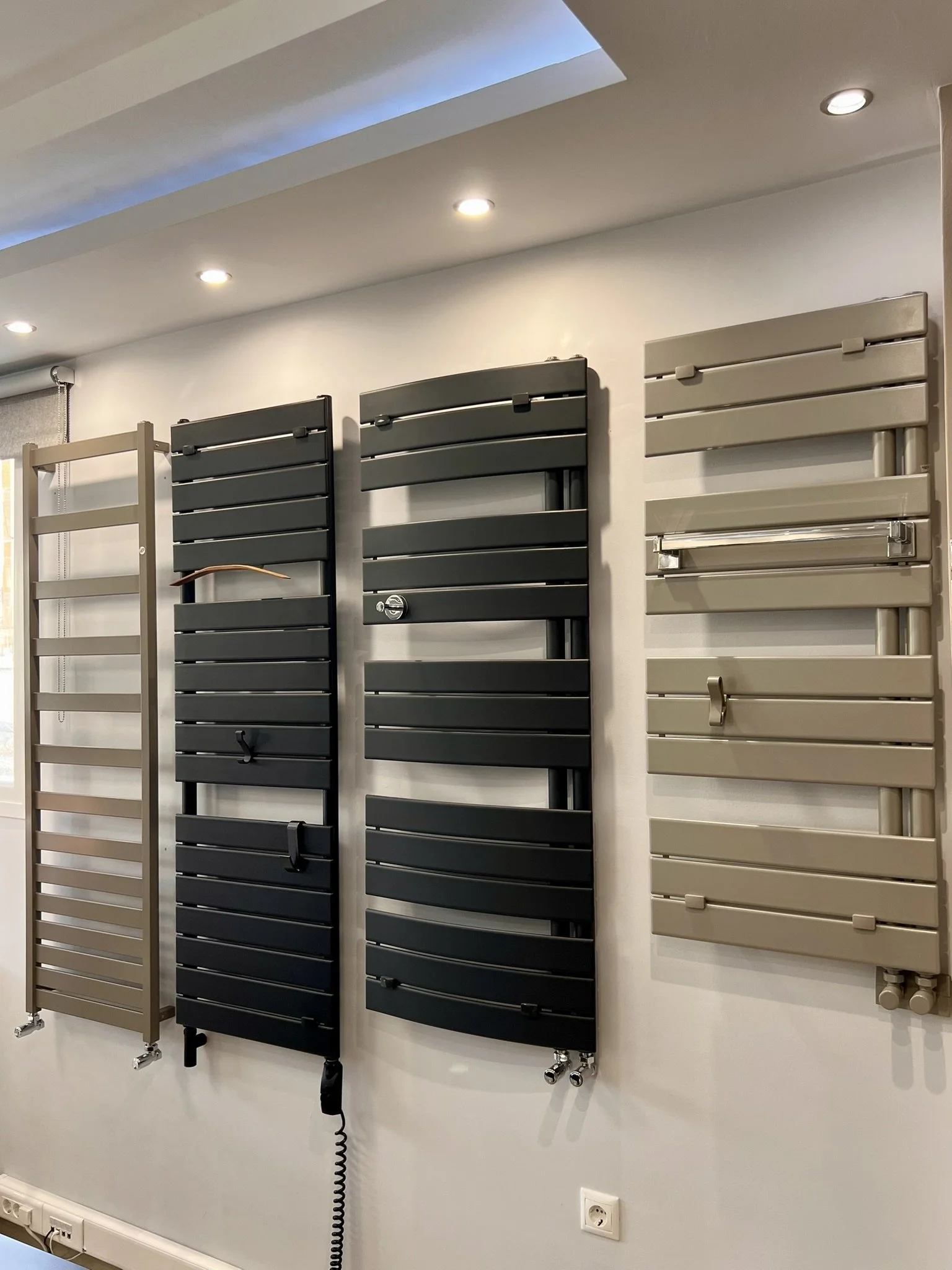 Interior view of the Tsolakidis showroom featuring a wide selection of modern decorative radiators, including vertical heating panels, mirror-style radiators, and colored designer units for both living spaces and bathrooms