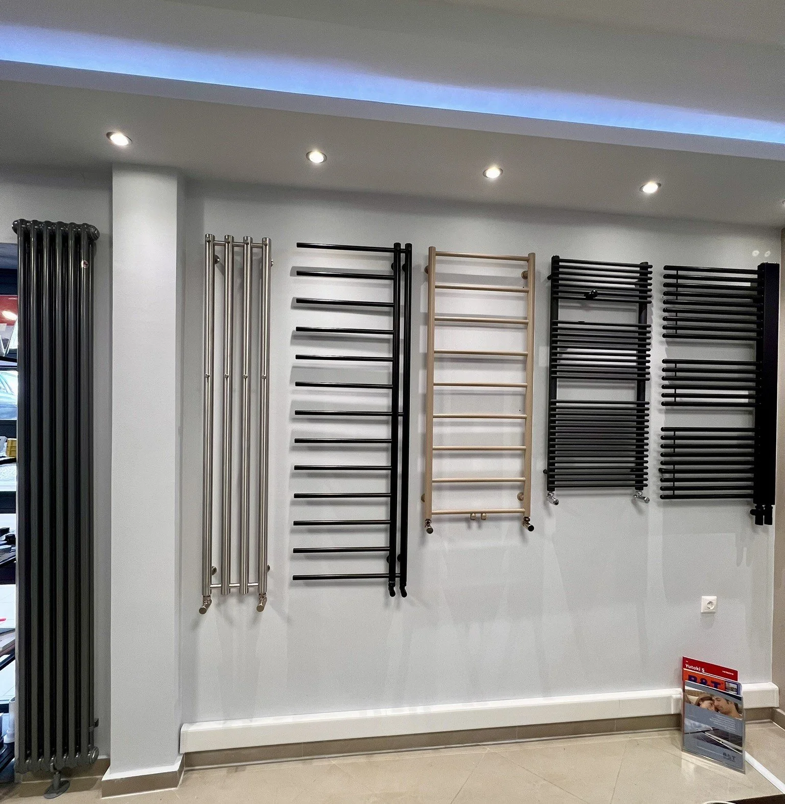 Interior view of the Tsolakidis showroom featuring a wide selection of modern decorative radiators, including vertical heating panels, mirror-style radiators, and colored designer units for both living spaces and bathrooms